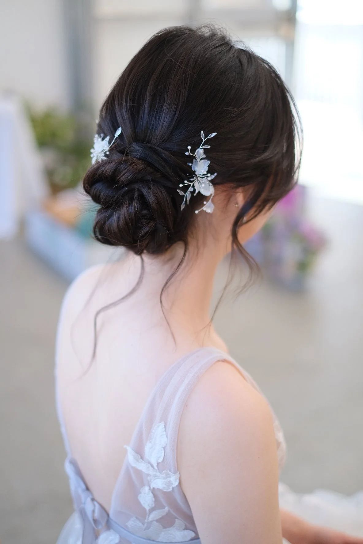 A woman with dark hair styled in an elegant updo with white floral hair accessories.