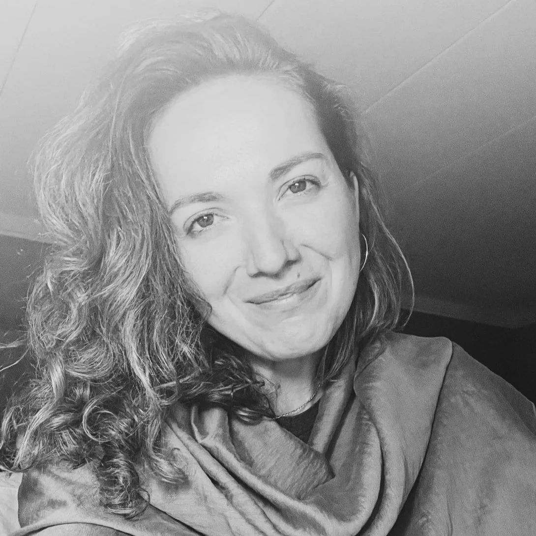 Black and white portrait of a smiling woman with curly hair, wearing a scarf and hoop earrings. Copyright Dasha Dare.
