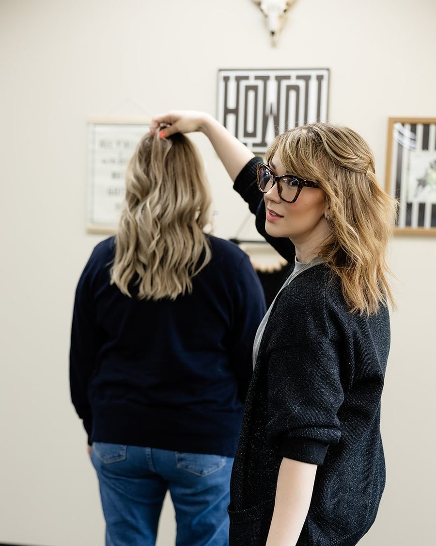 Blair Wilcox lifting a section of a client’s dimensional blonde highlights at WAREHAUS Hair Studio in Manchester, Tennessee