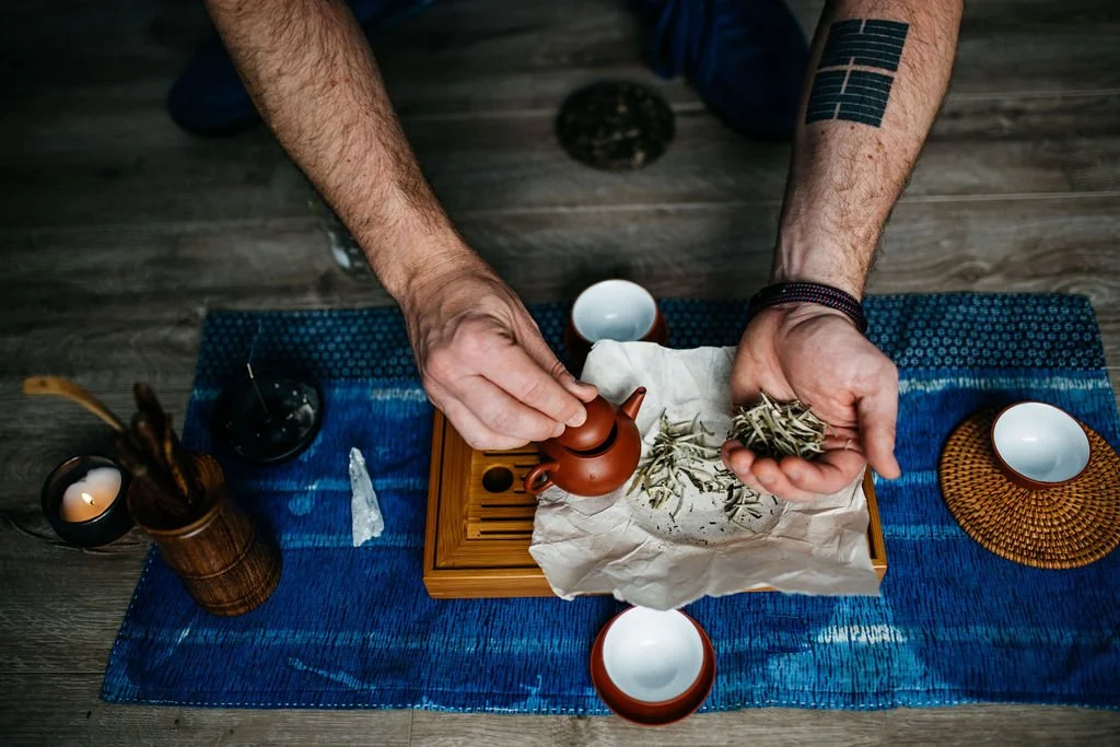 Overhead view of hands preparing ceremonial-grade tea on a wooden tray with indigo cloth in Portland