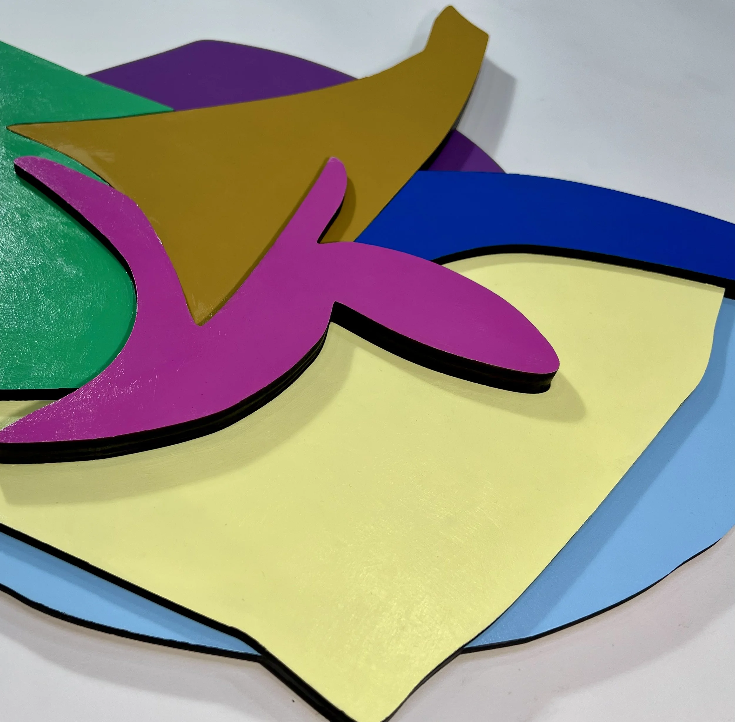 Close-up of colorful, layered paper cutouts in various shapes and colors including purple, yellow, blue, green, and brown.