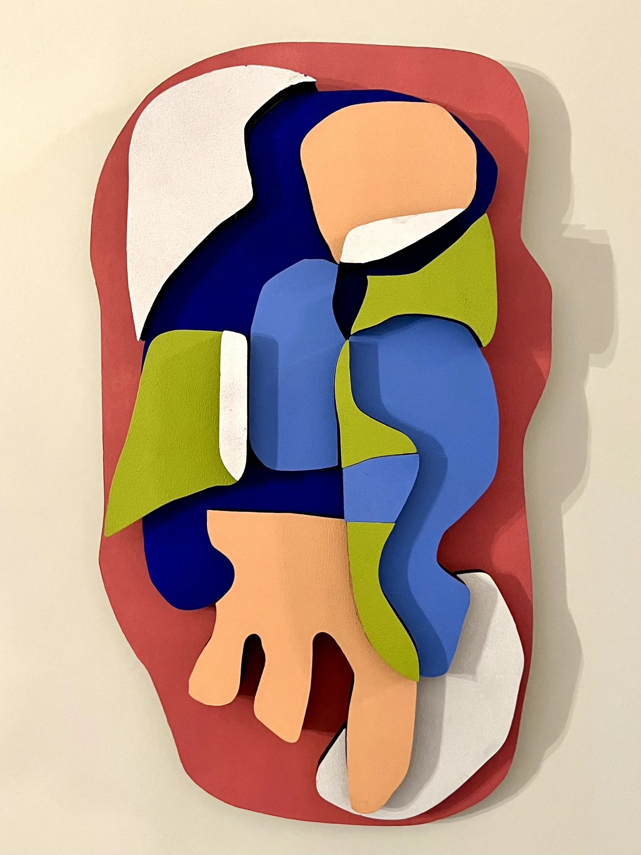 Abstract, colorful paper sculpture featuring various shapes and colors like blue, green, peach, white, black, and red, arranged in a layered composition.