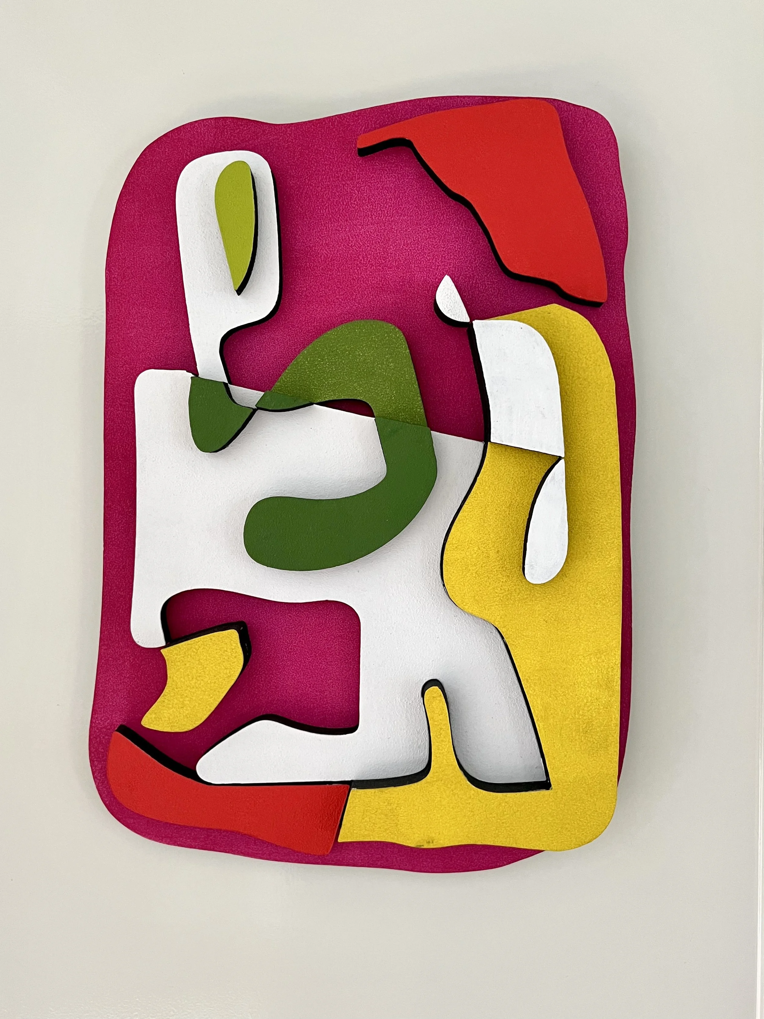 Abstract colorful wall art with irregular shapes in red, green, yellow, white, and black on a pink background.