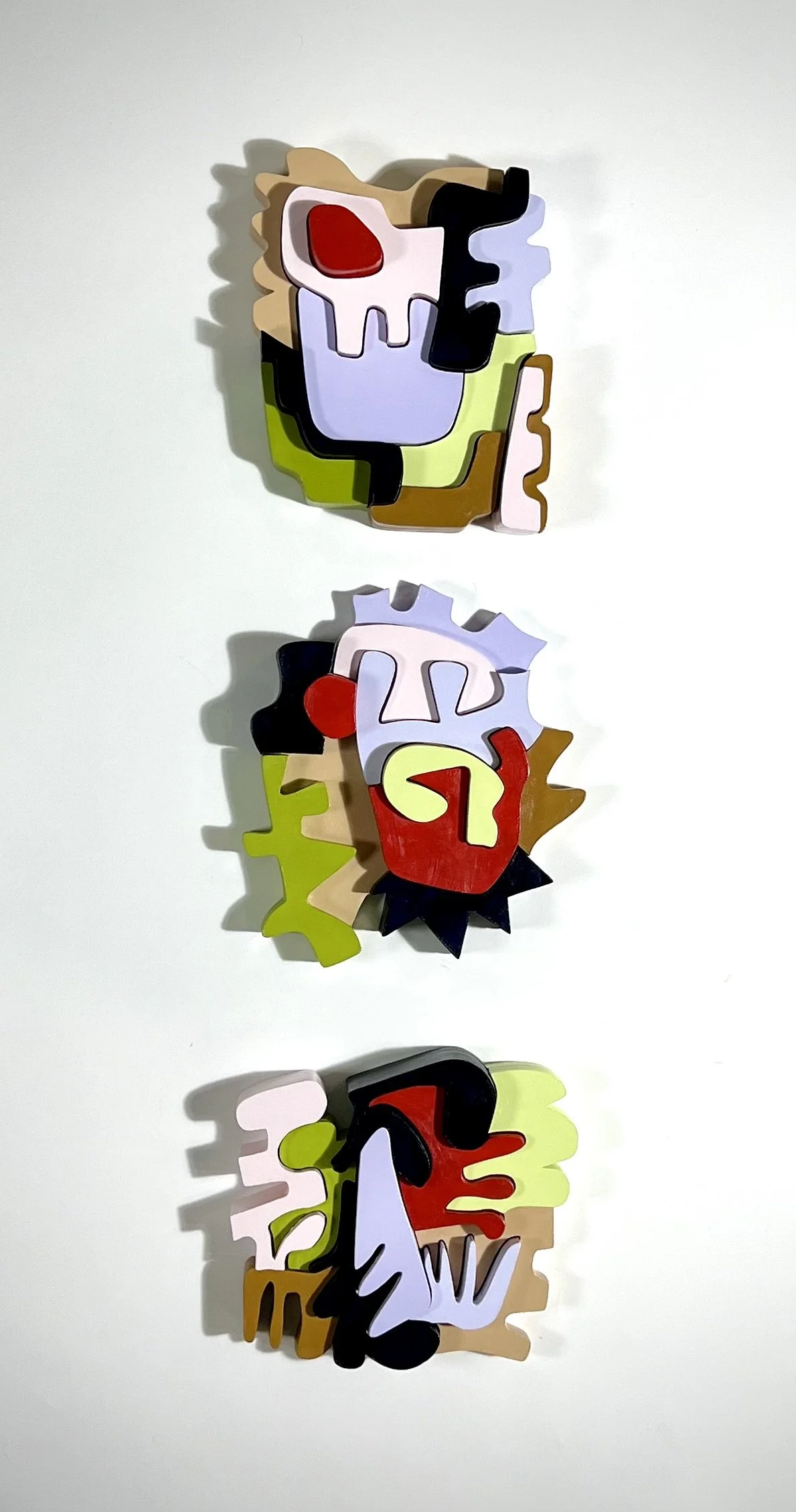 Colorful abstract wood puzzle pieces arranged in three separate clusters on a white background.