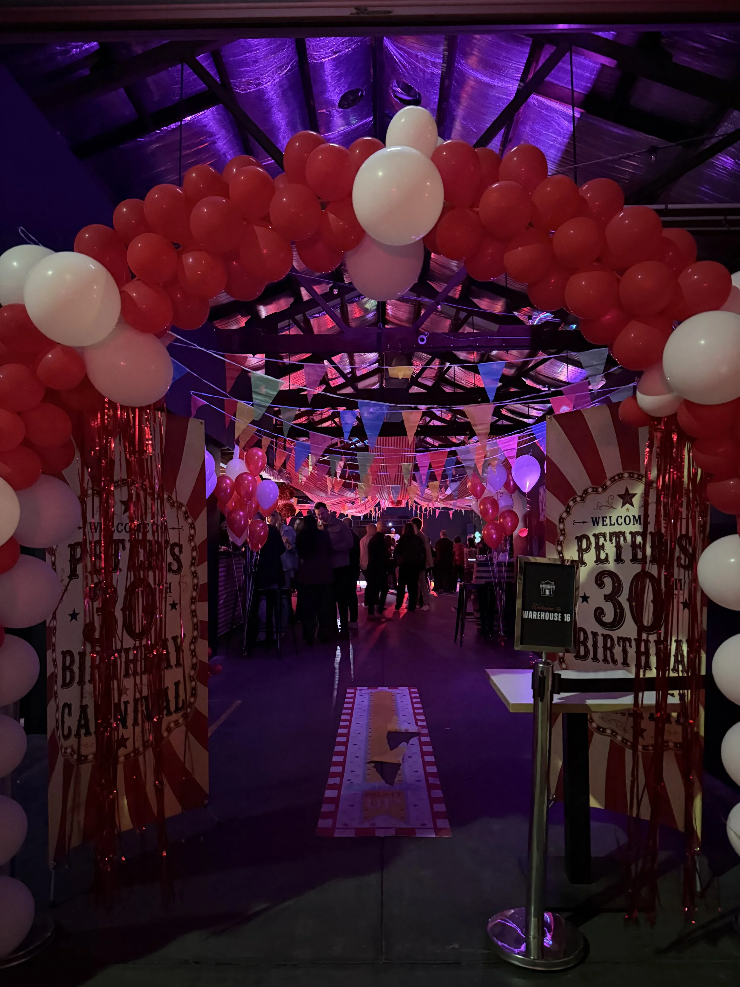 Red and white balloon arch at a 30th birthday party at Warehouse 16