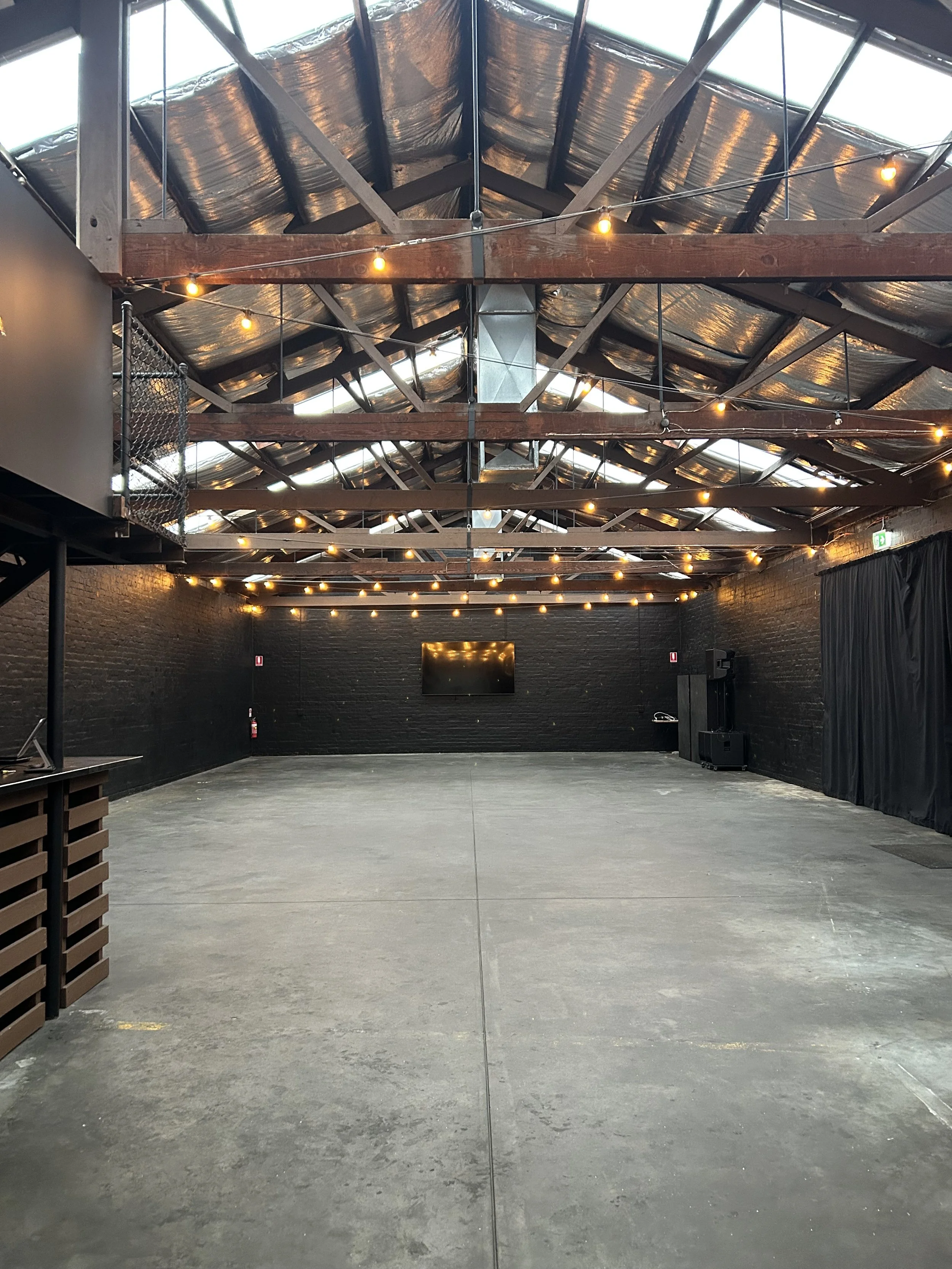 Empty Warehouse 16 event space with exposed trusses and festoon lights, Adelaide
