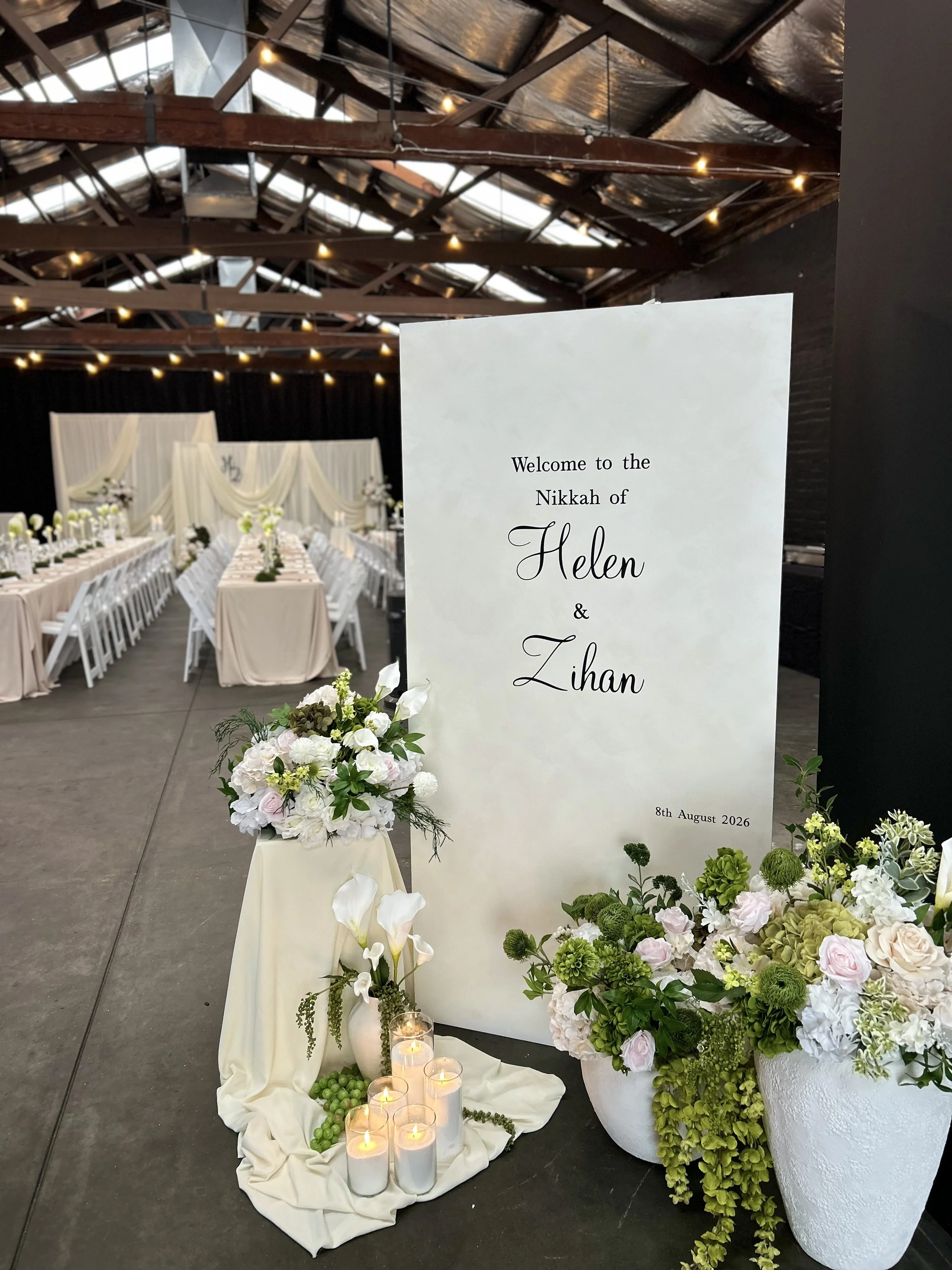 Welcome sign and white flowers at a wedding reception at Warehouse 16