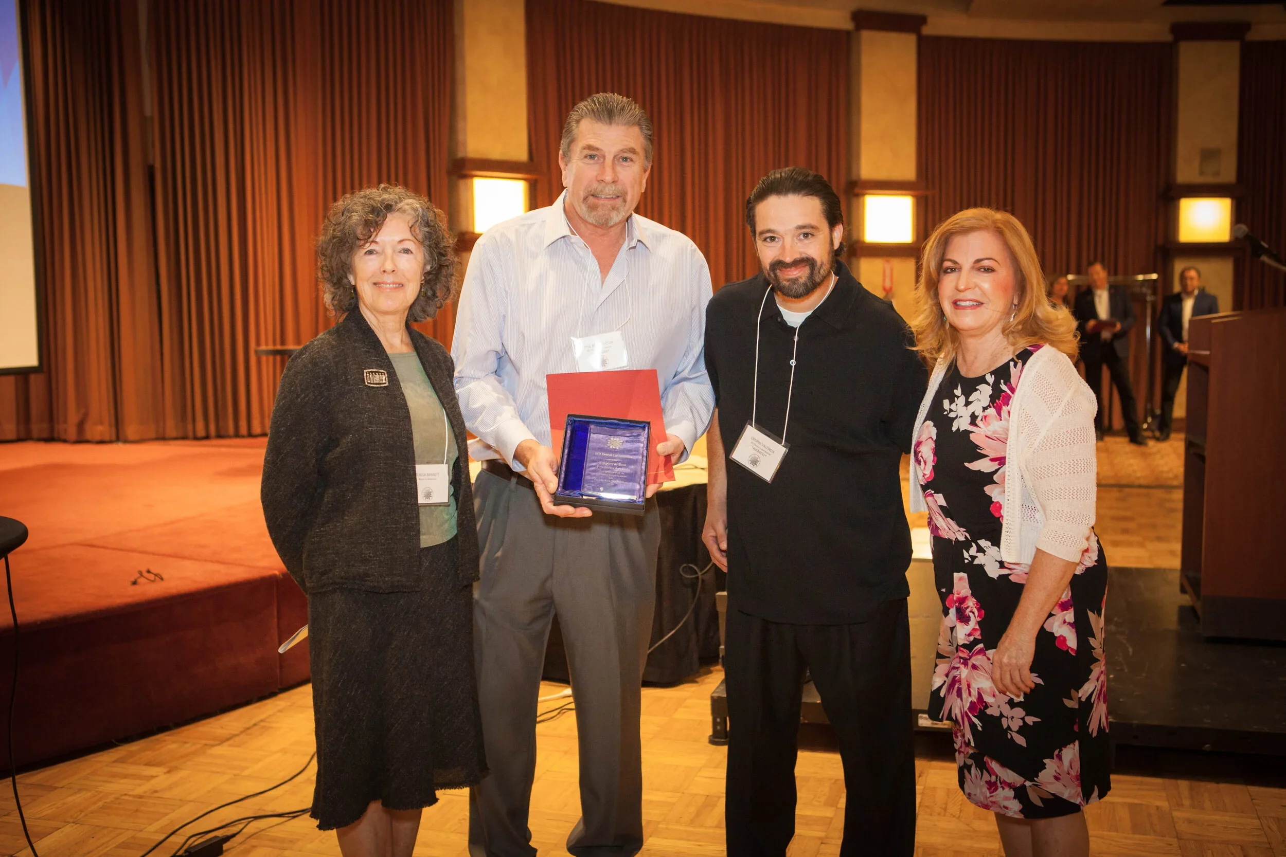 Four people standing for photo, one holding award.