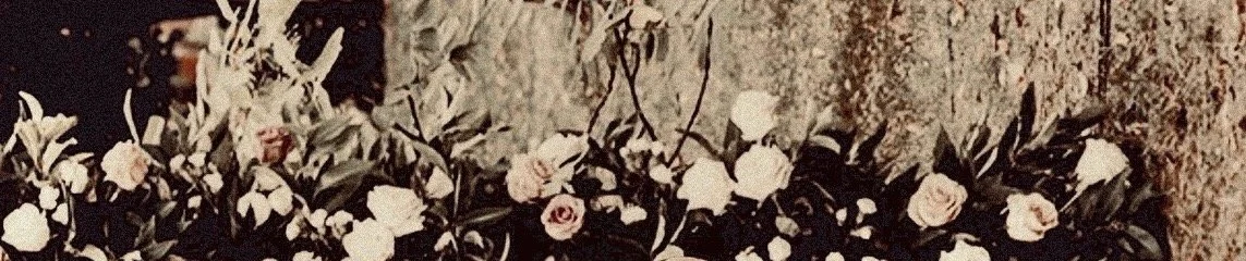 A floral arrangement with pink roses and assorted white and dark flowers and greenery.