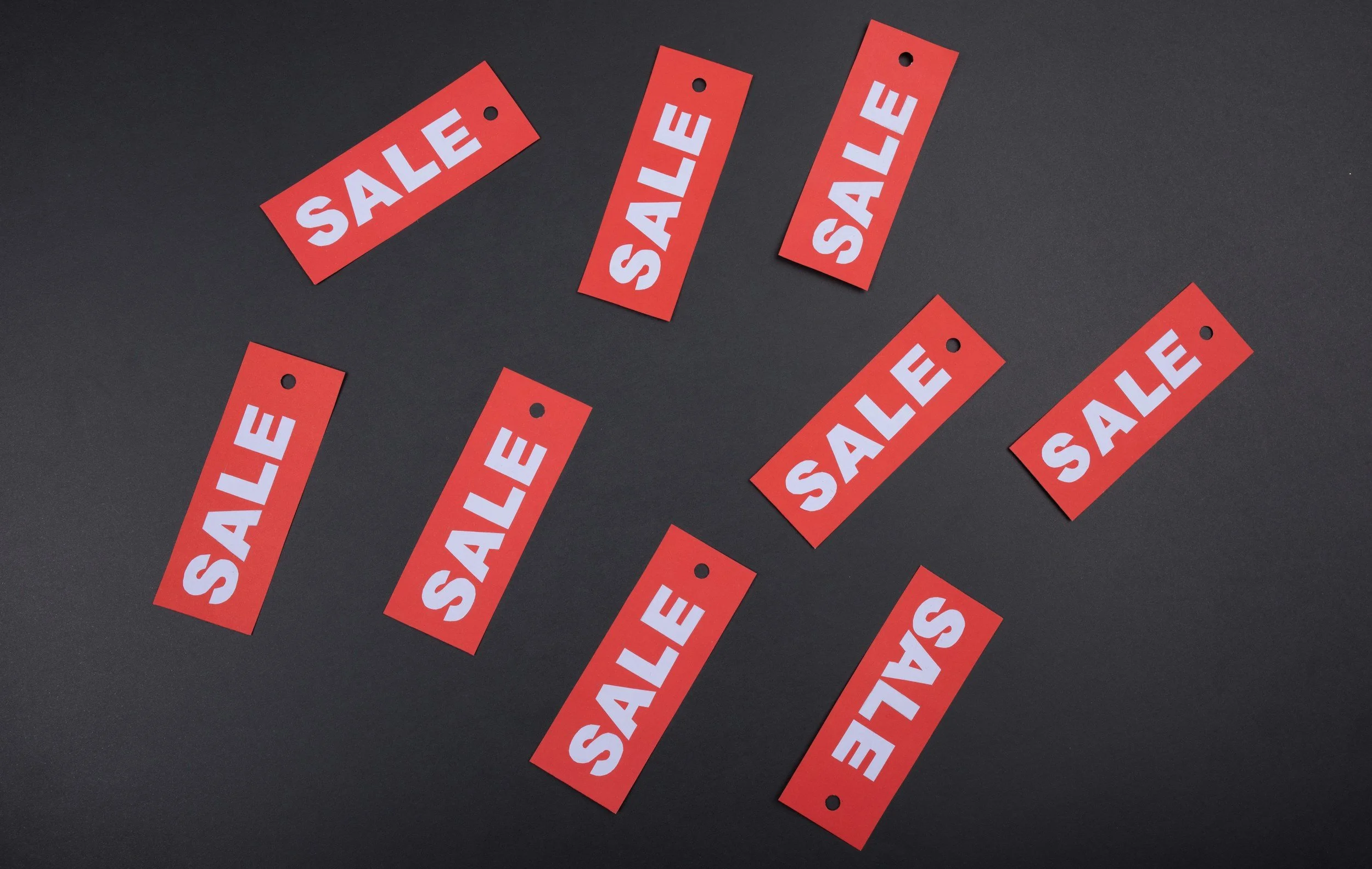 Multiple red sale tags with white text scattered on a dark surface.