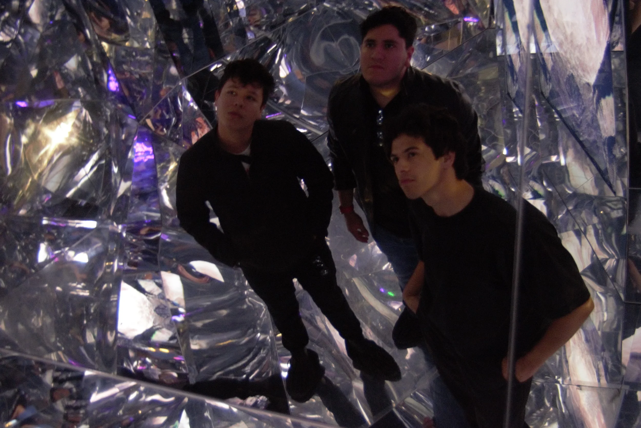 Promo shot of Drew, Moi, and Daniel looking off into a reflection at the WNDR Museum in San Diego.