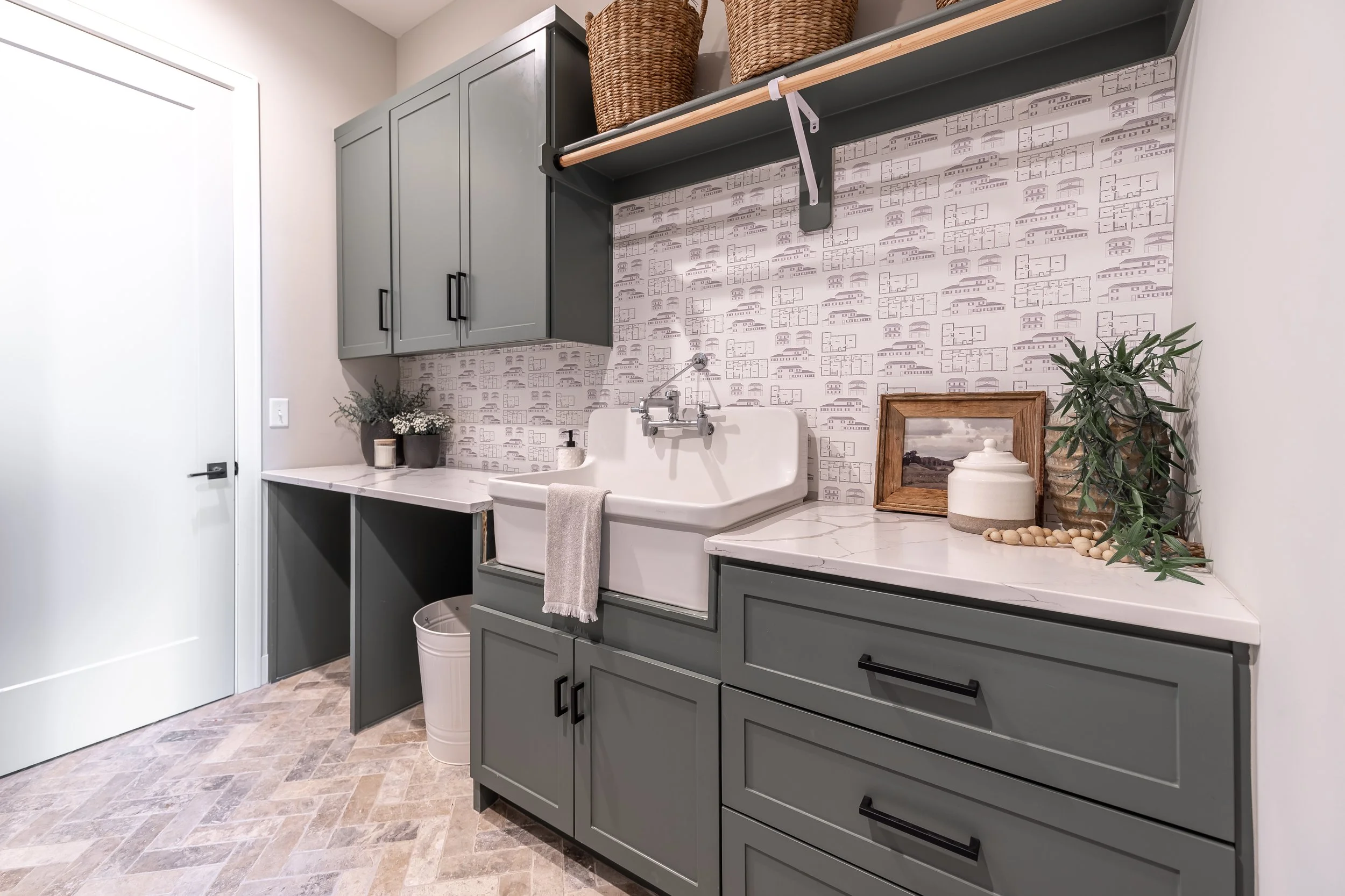 Luxury laundry room with muted green cabinets and white farmhouse sink