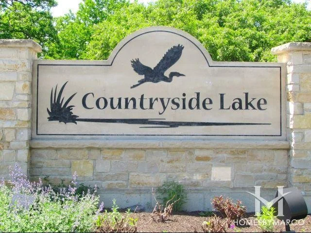 Sign for Countryside Lake with silhouette of an eagle flying above lake and grass.