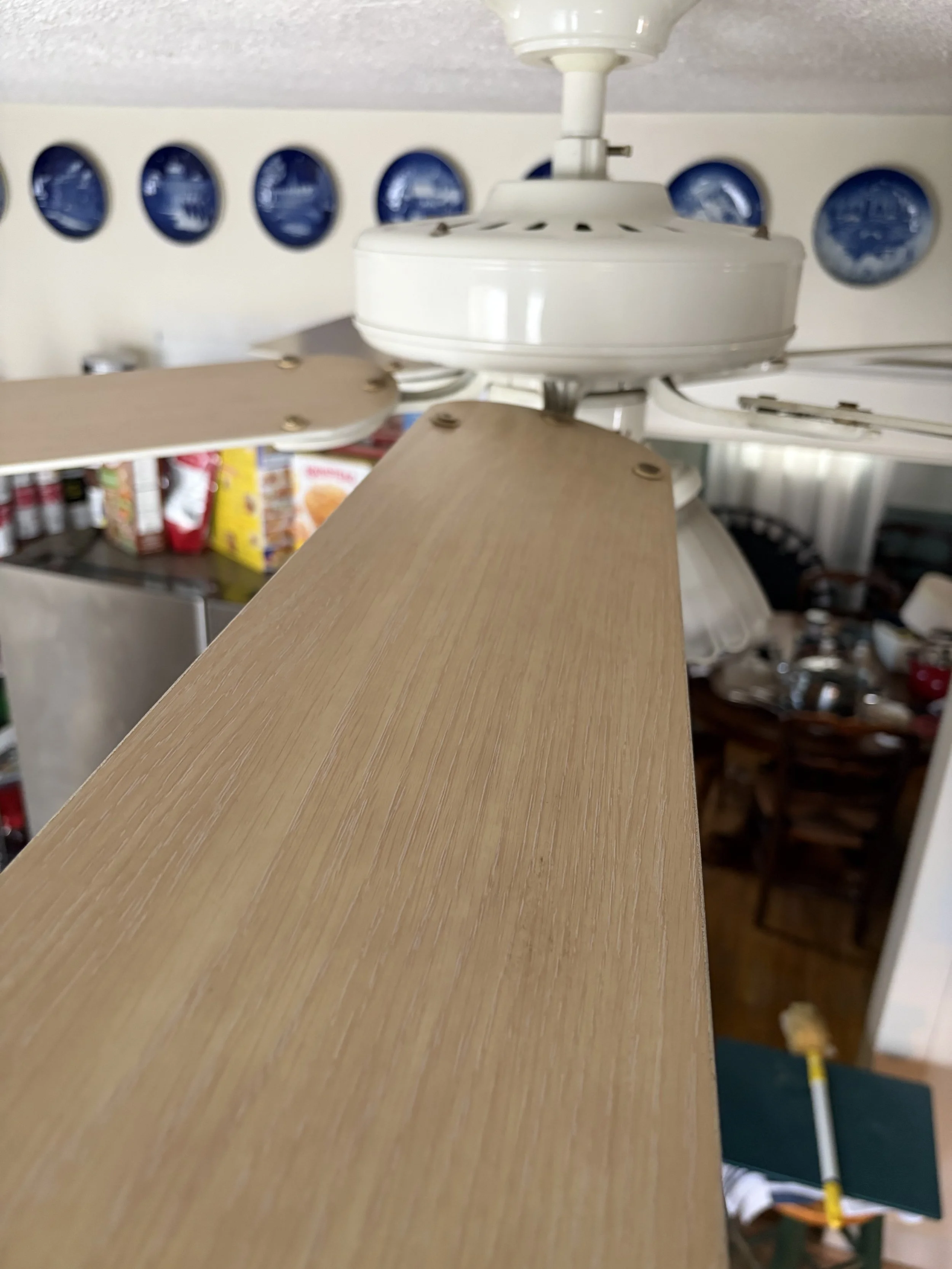 After it was cleaned, a close-up of a ceiling fan with wooden blades in a room. Clean, fresh detail.