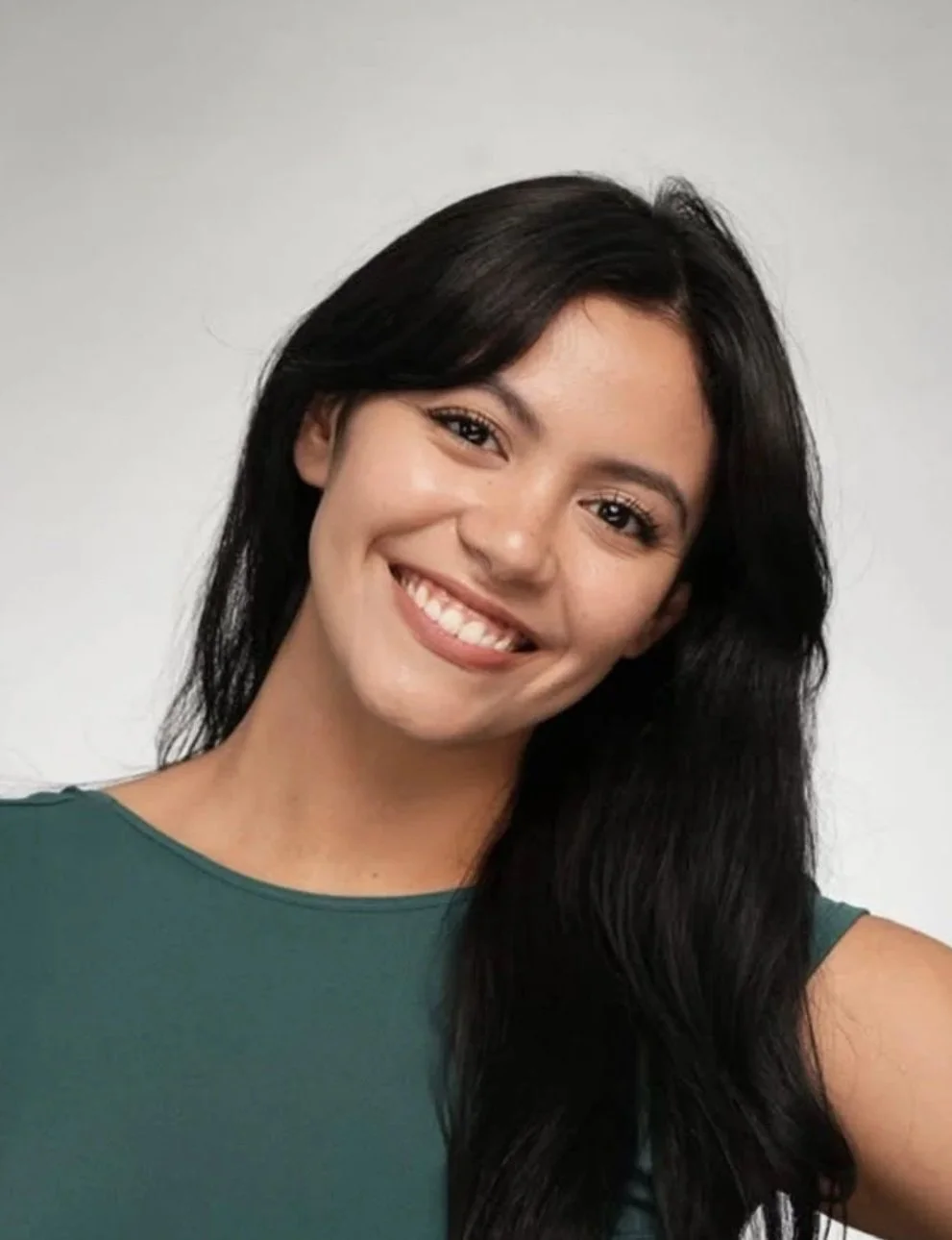 A woman with long dark hair smiling and wearing a sleeveless green top.