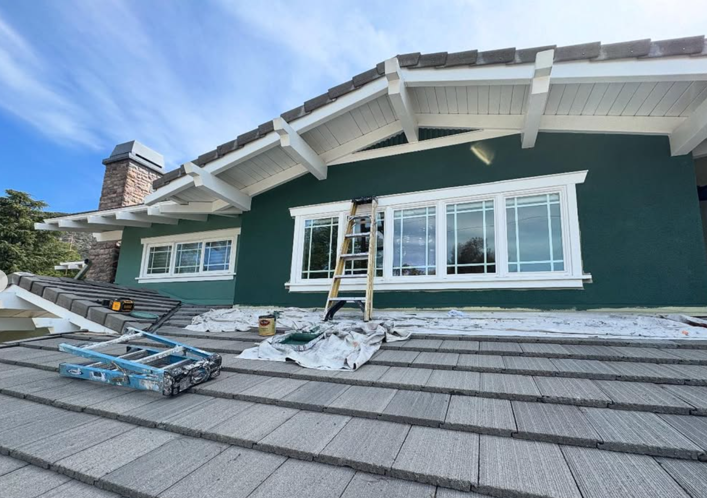 Exterior painting and stucco repair project by Repairs y More featuring fresh dark green paint on the stucco walls, crisp white trim, and updated roofing details on a residential home in Los Angeles County.
