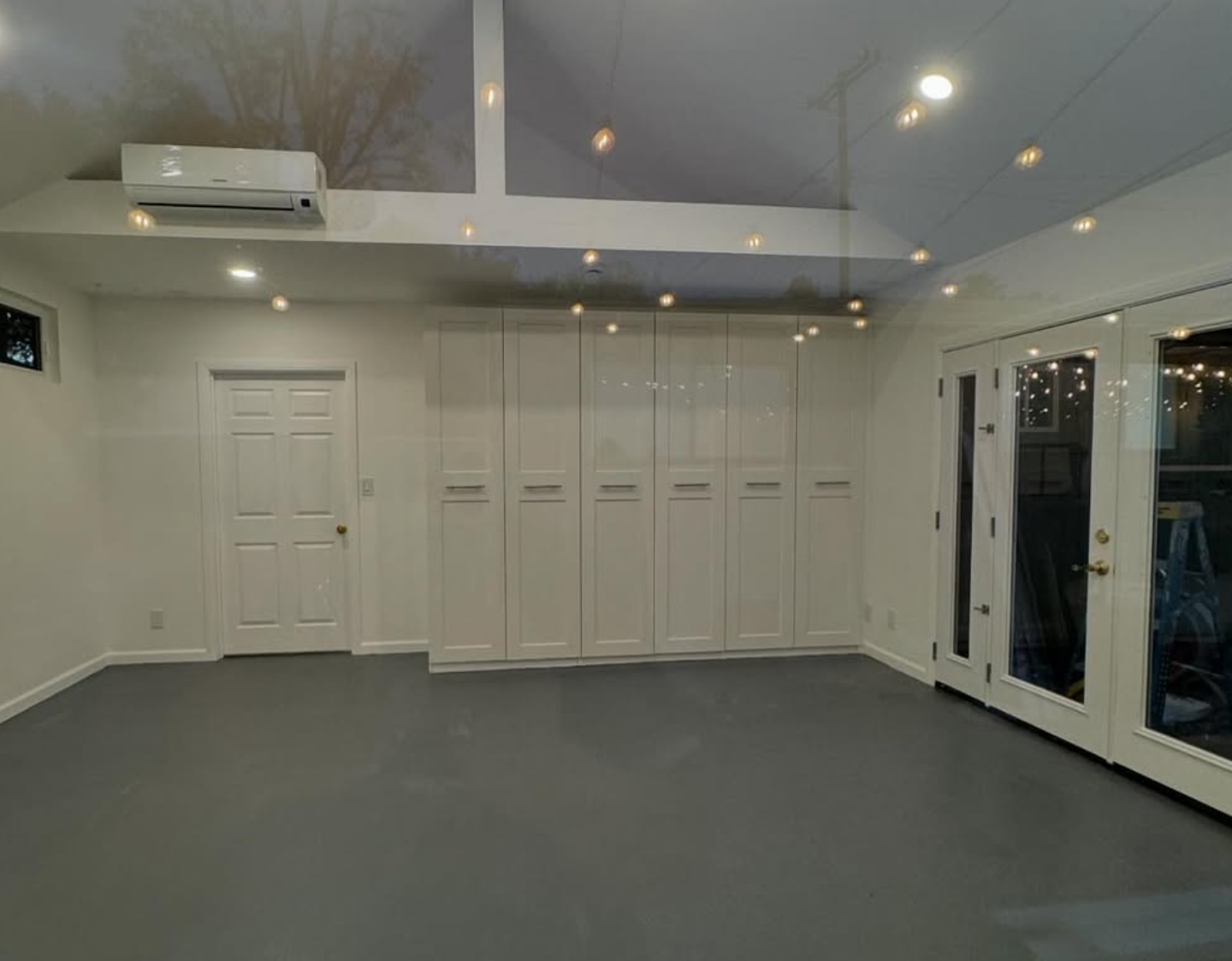 Garage conversion project by Repairs y More transformed into a bright ADU space with white built-in cabinets, grey epoxy flooring, and new windows and doors in Los Angeles County.