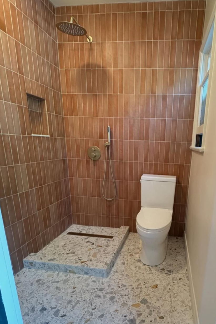 Bathroom renovation by Repairs y More featuring warm terracotta tile walls, a spacious terrazzo floor, and a modern walk-in shower with brass fixtures in a Los Angeles area home.