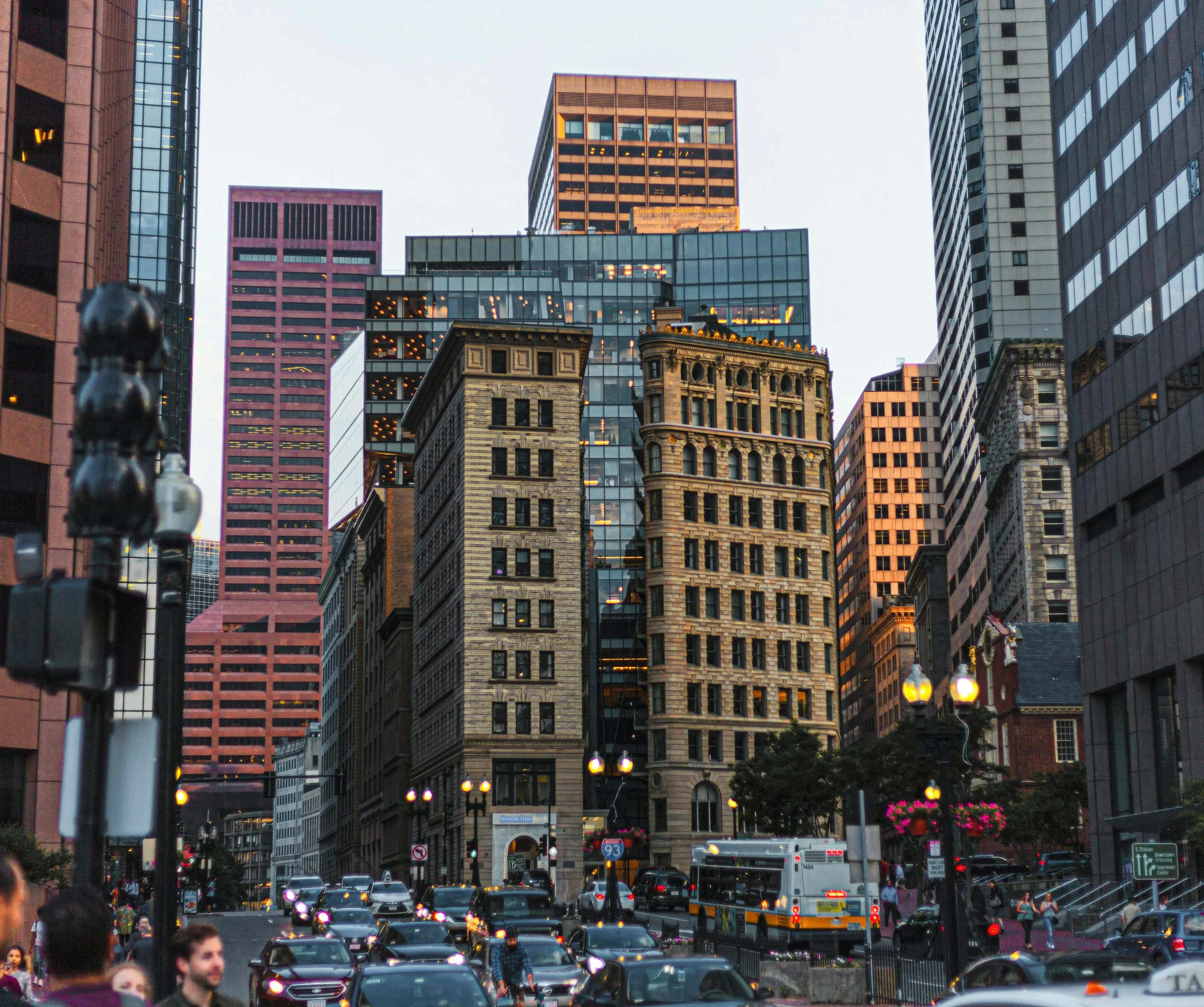 City street scene with tall skyscrapers, cars, and pedestrians.