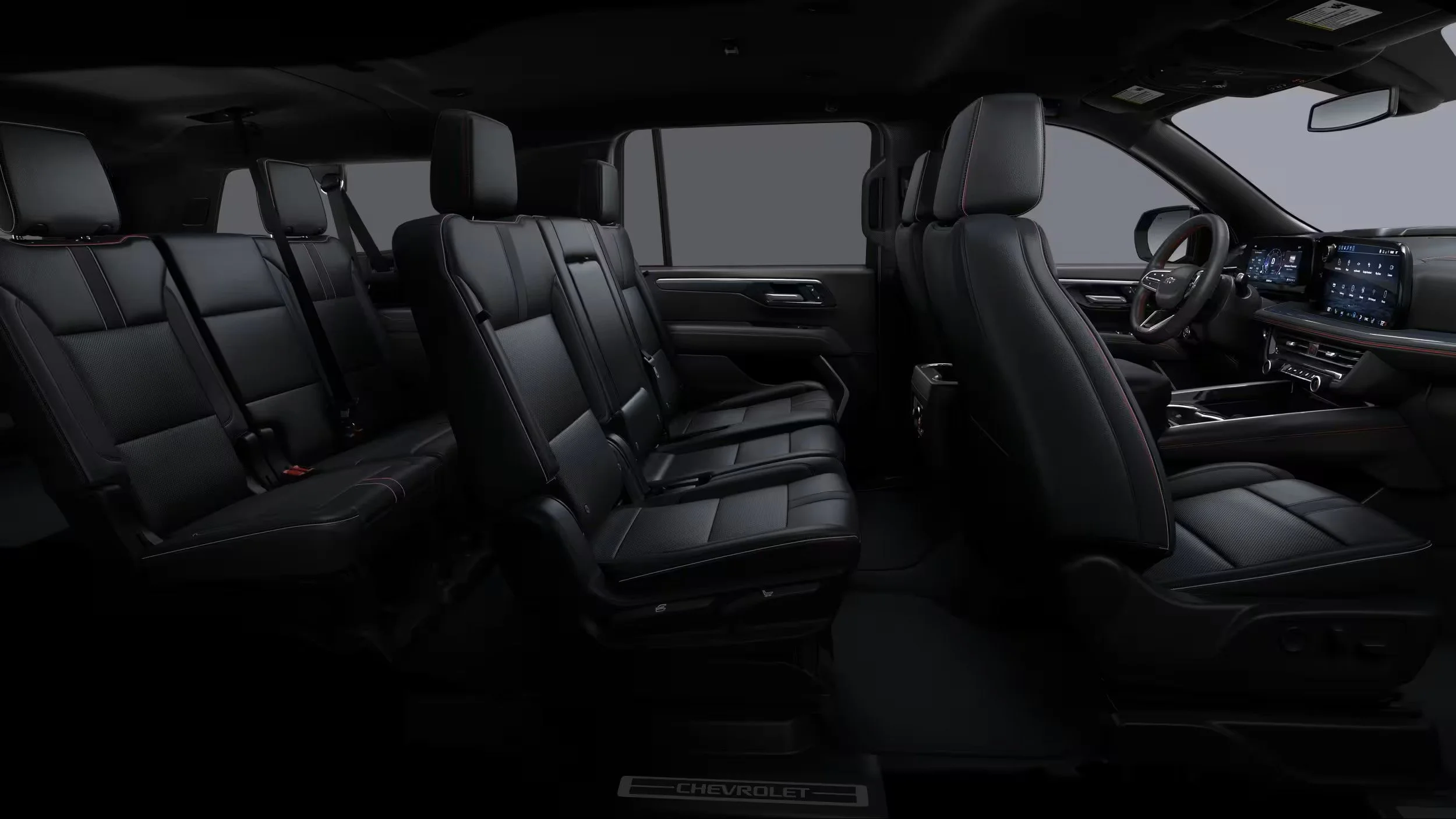 The interior of a black Chevrolet SUV with three rows of leather seats, an electronic dashboard, and a steering wheel.