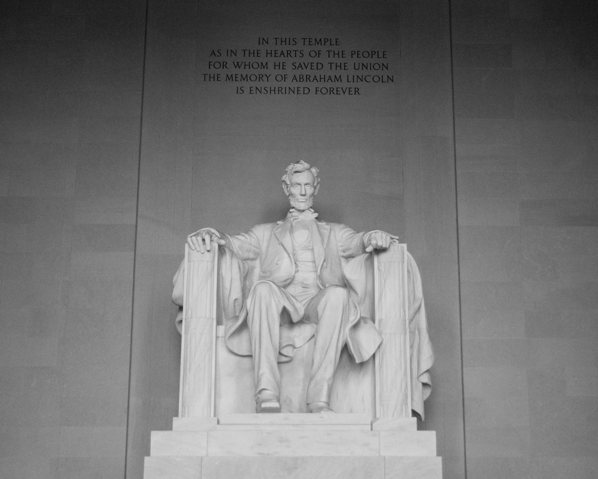 The Lincoln Memorial, a large white marble monument, featuring a seated statue of Abraham Lincoln with inscriptions on the wall behind.