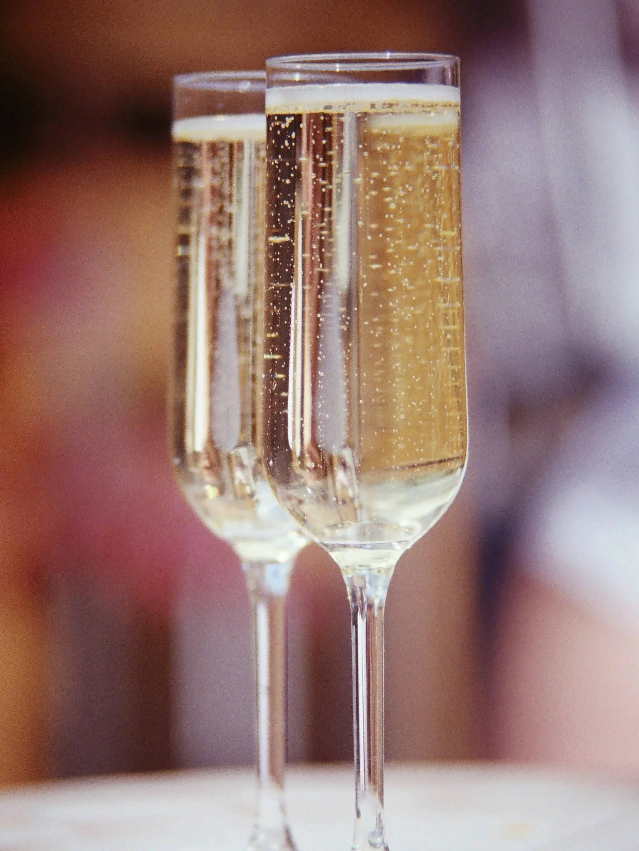 Two champagne glasses being held up, filled with bubbly champagne.