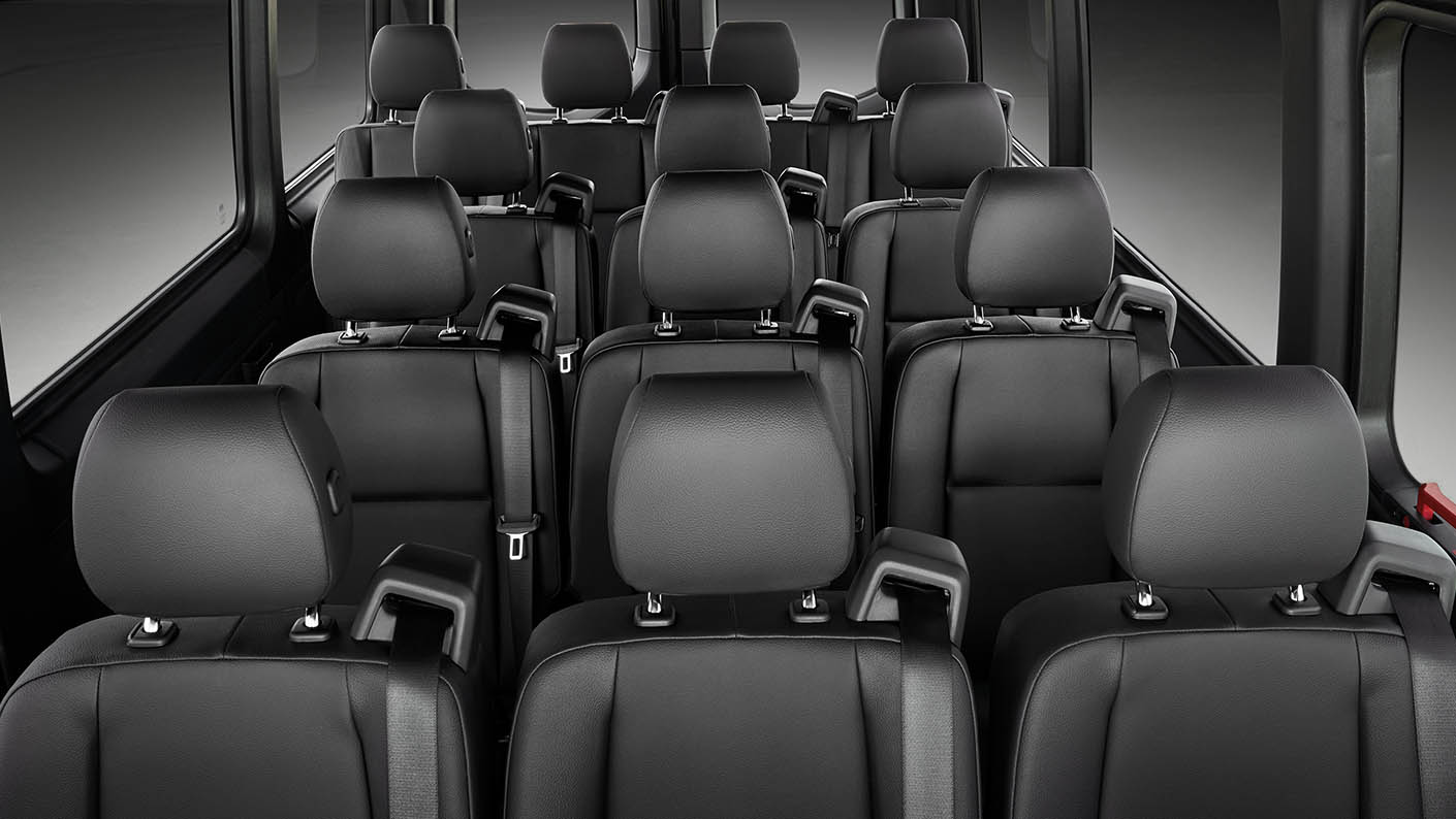 Interior view of a bus with multiple black leather seats arranged in rows.