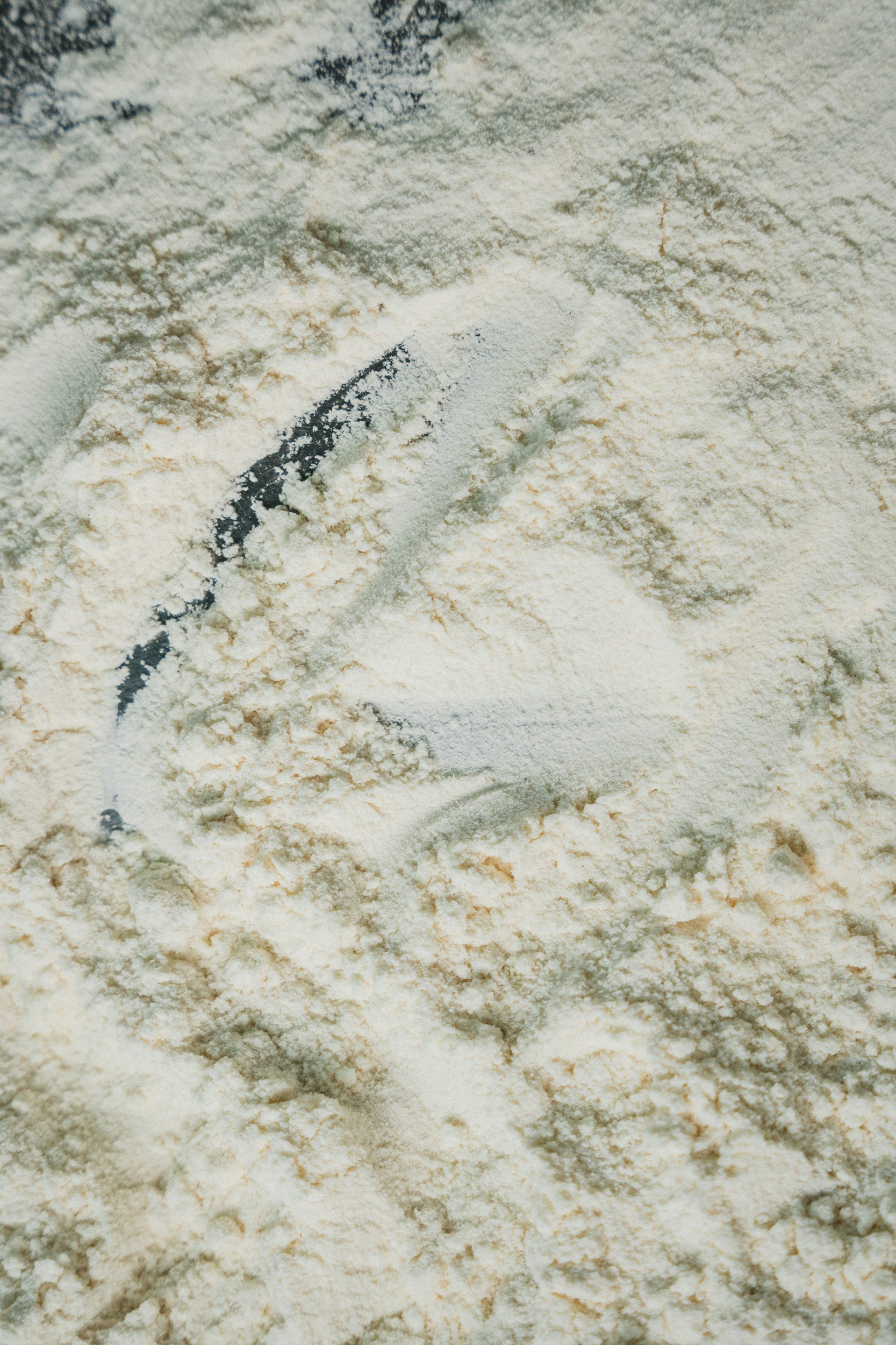 Close-up of powdered protein supplement with a scoop partially buried in the powder.