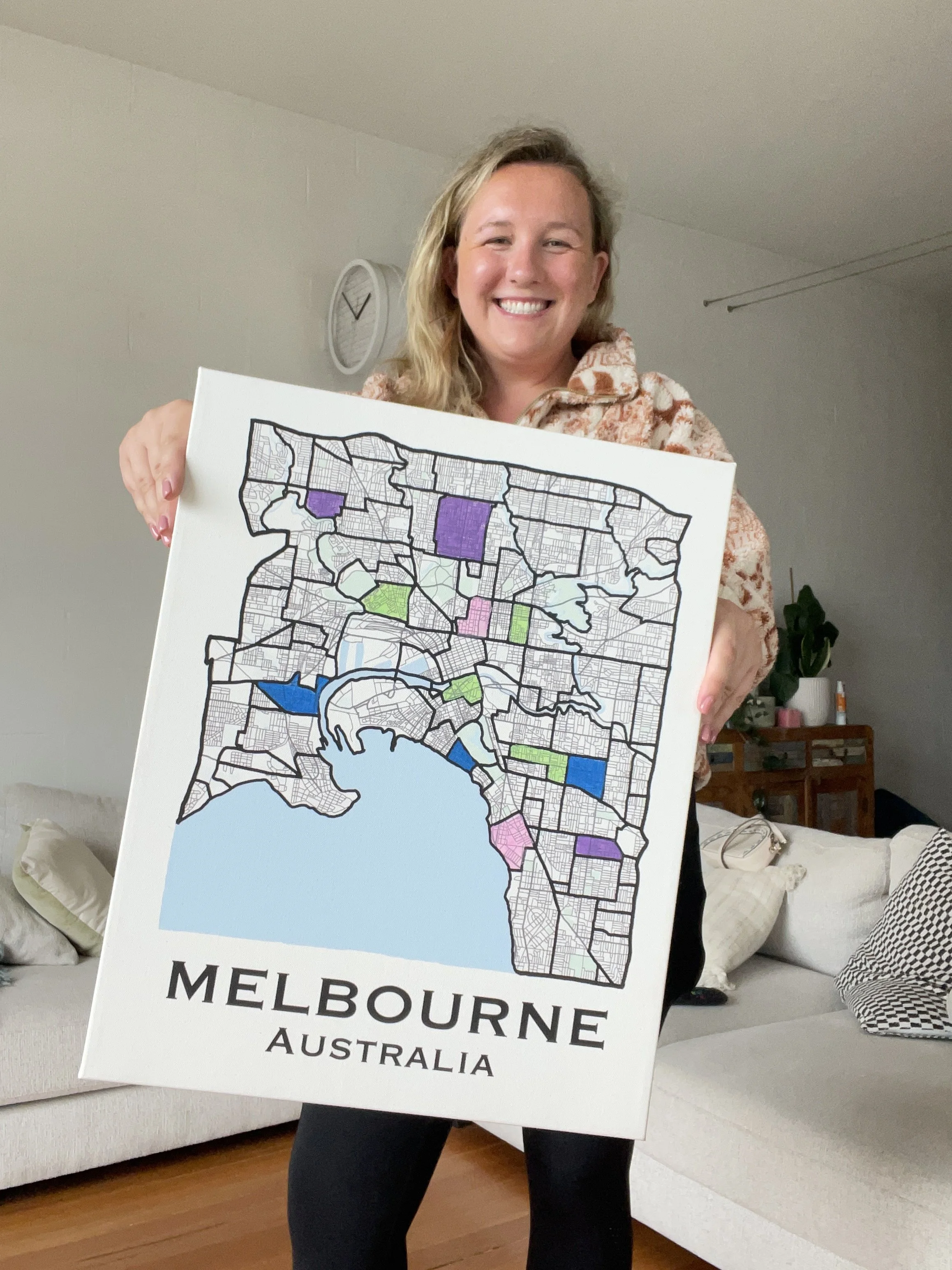 Person smiling holding a map of Melbourne, Australia, in a living room.