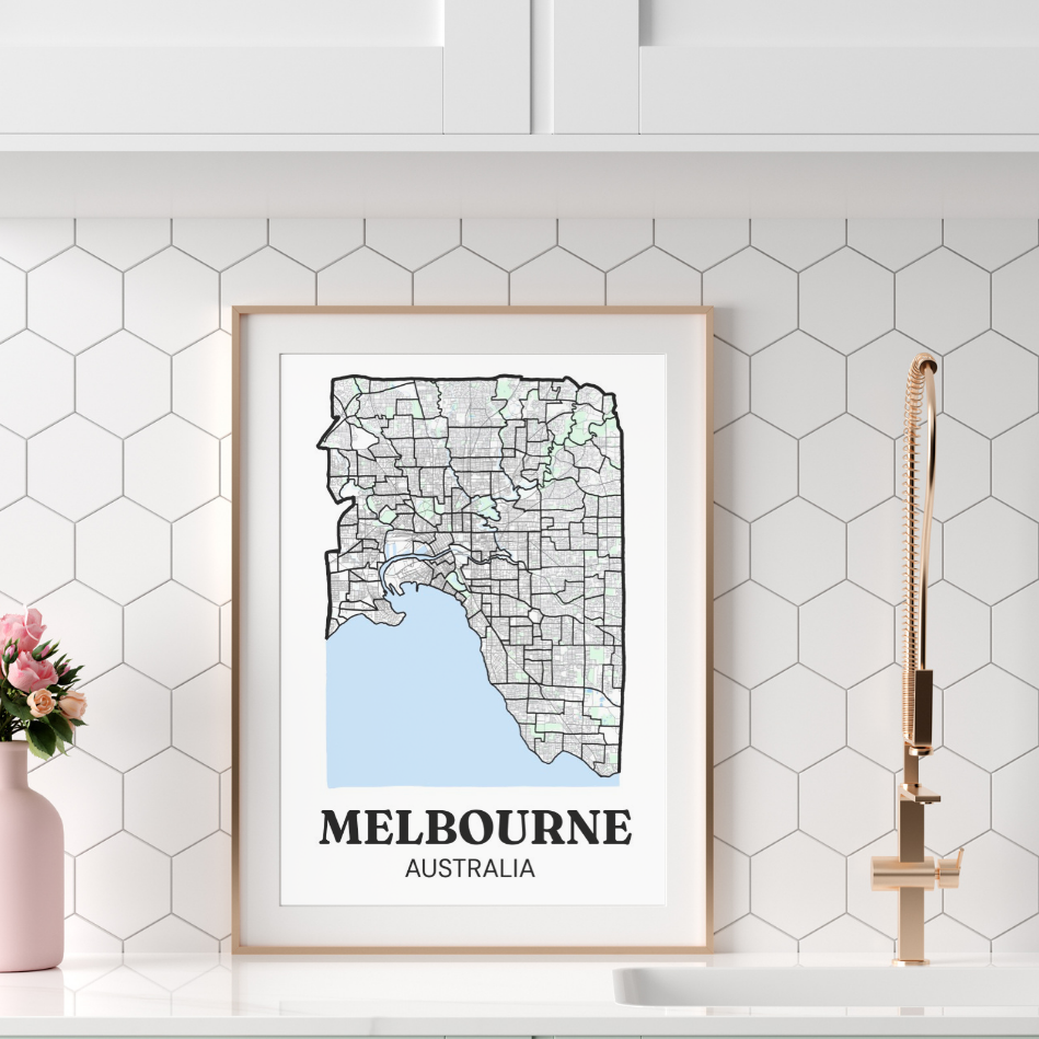 Framed map of Melbourne, Australia, on a white hexagonal tile backsplash in a modern kitchen with a pink vase of flowers and a bronze faucet.