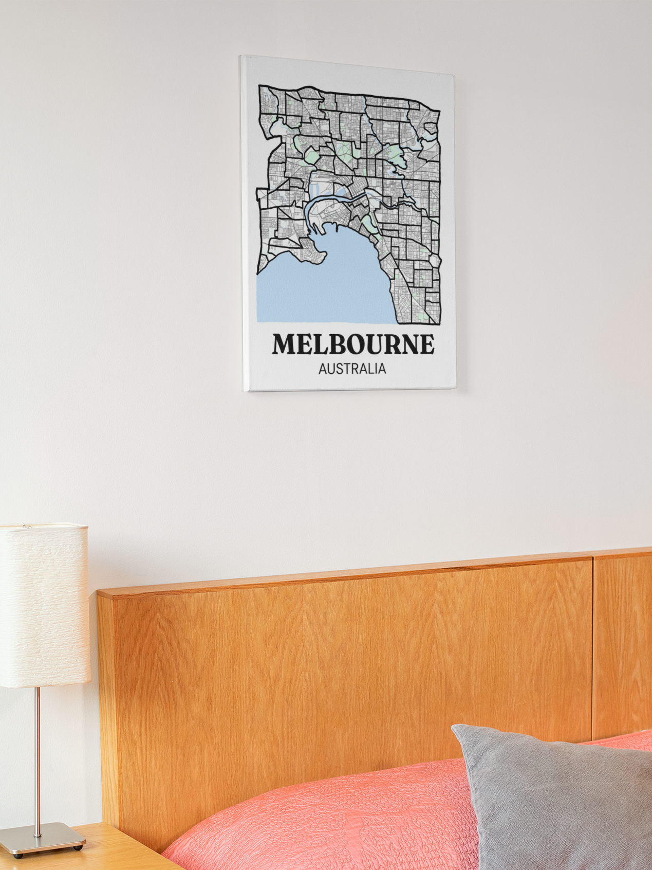 Melbourne inner suburb map canvas hanging above a wooden bed with pink bedding and a grey cushion.