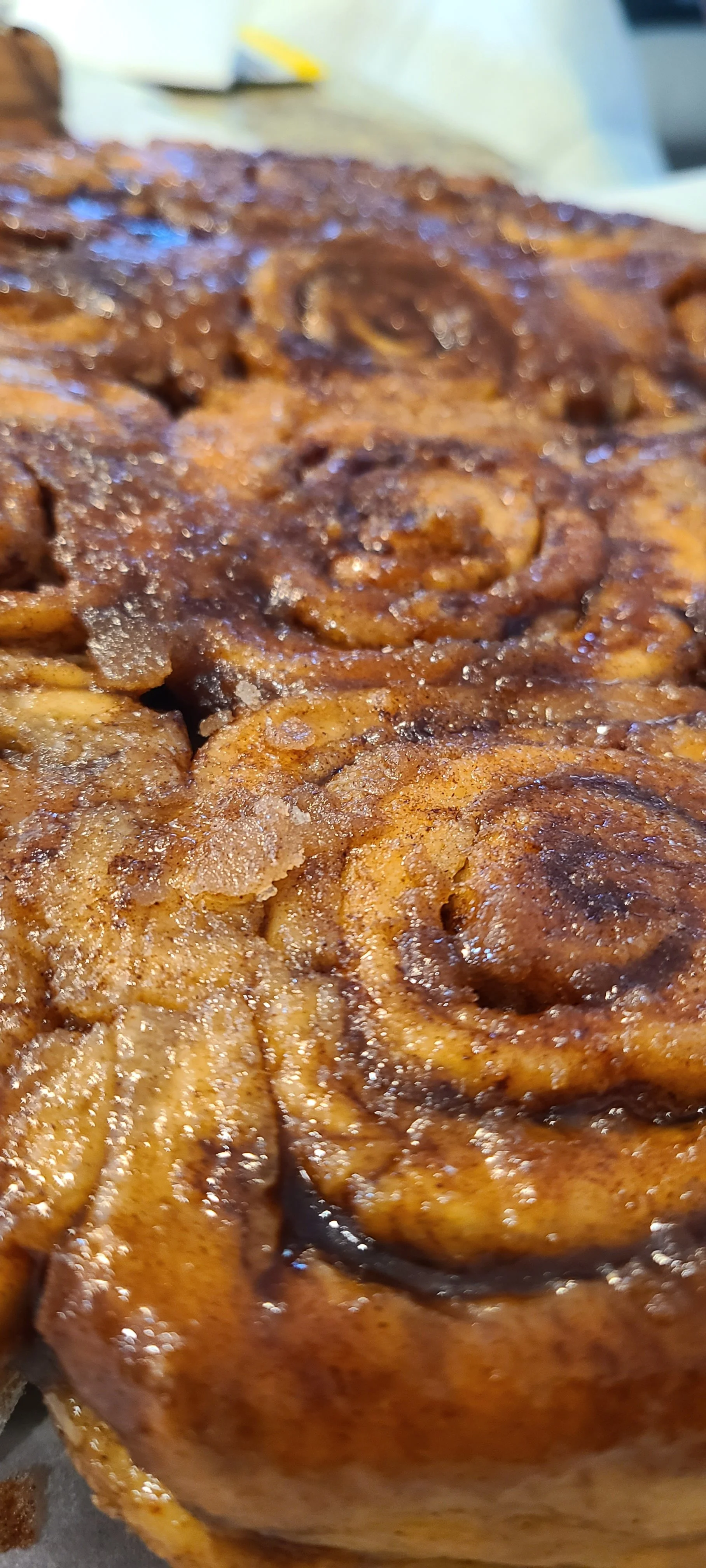 Close-up of freshly baked cinnamon rolls topped with sugar and cinnamon.