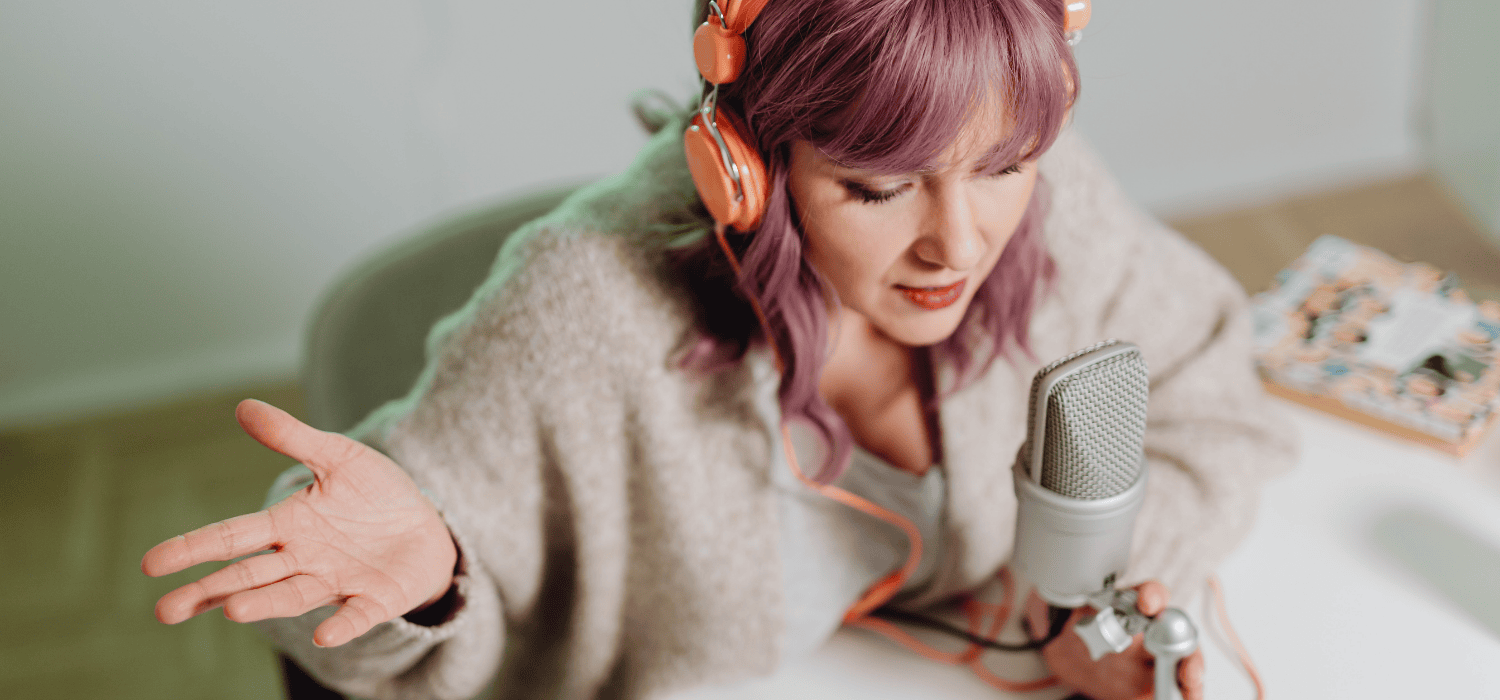 Lady live streaming with headphones on and talking into a microphone