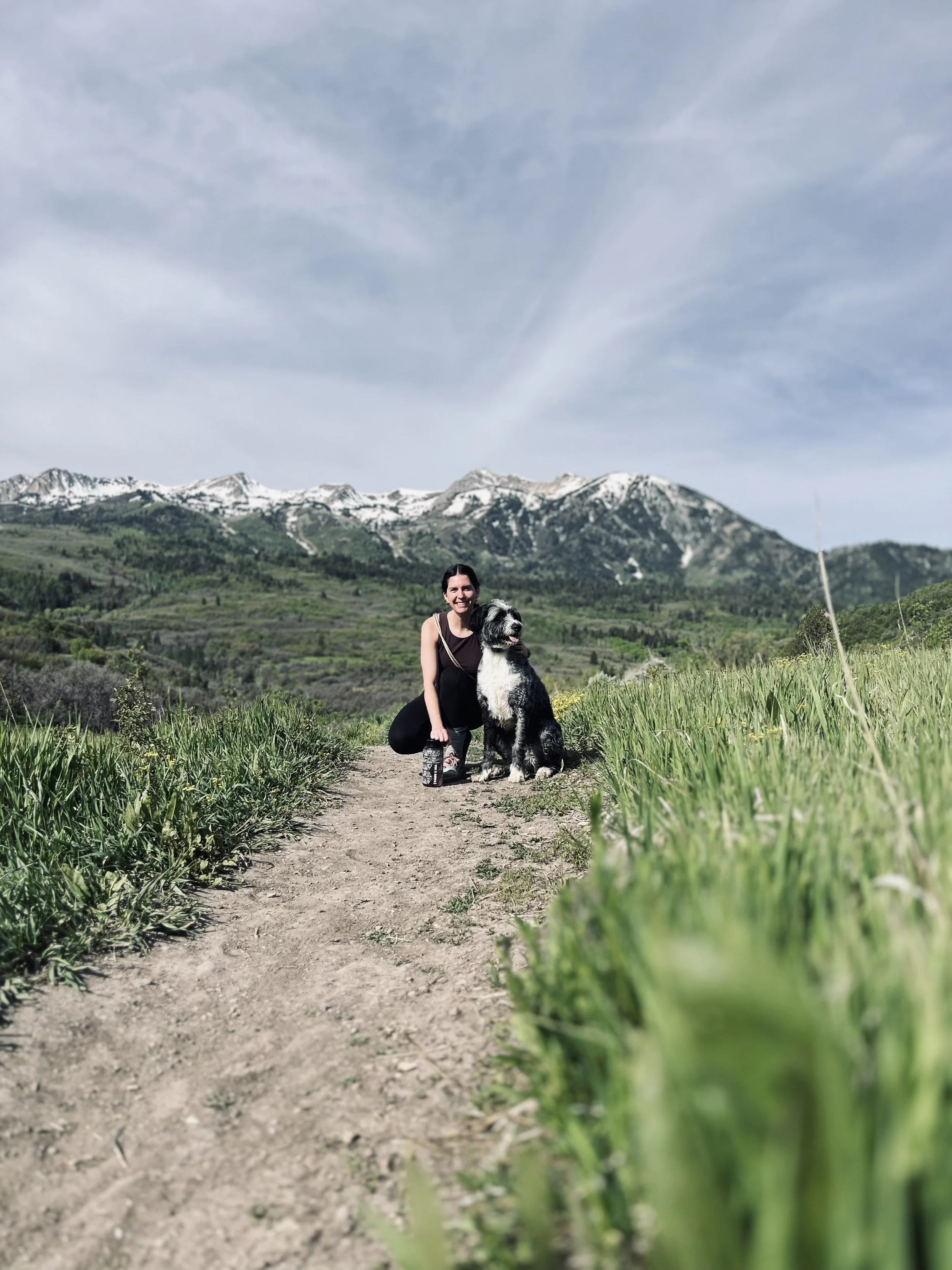 Esty and Oakley on a mountain trail in northern Utah with snow-capped Wasatch peaks in the background