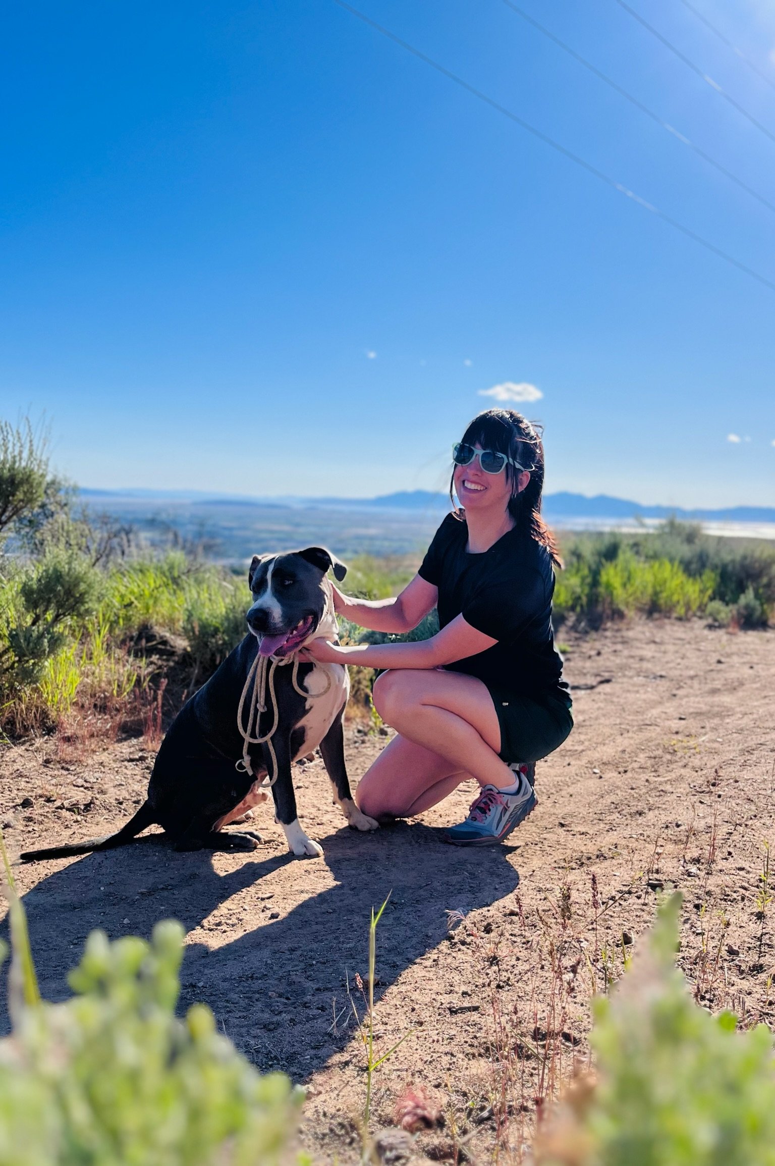 Esty with a dog on a trail overlooking Northern Utah during a Trailhead community adventure.