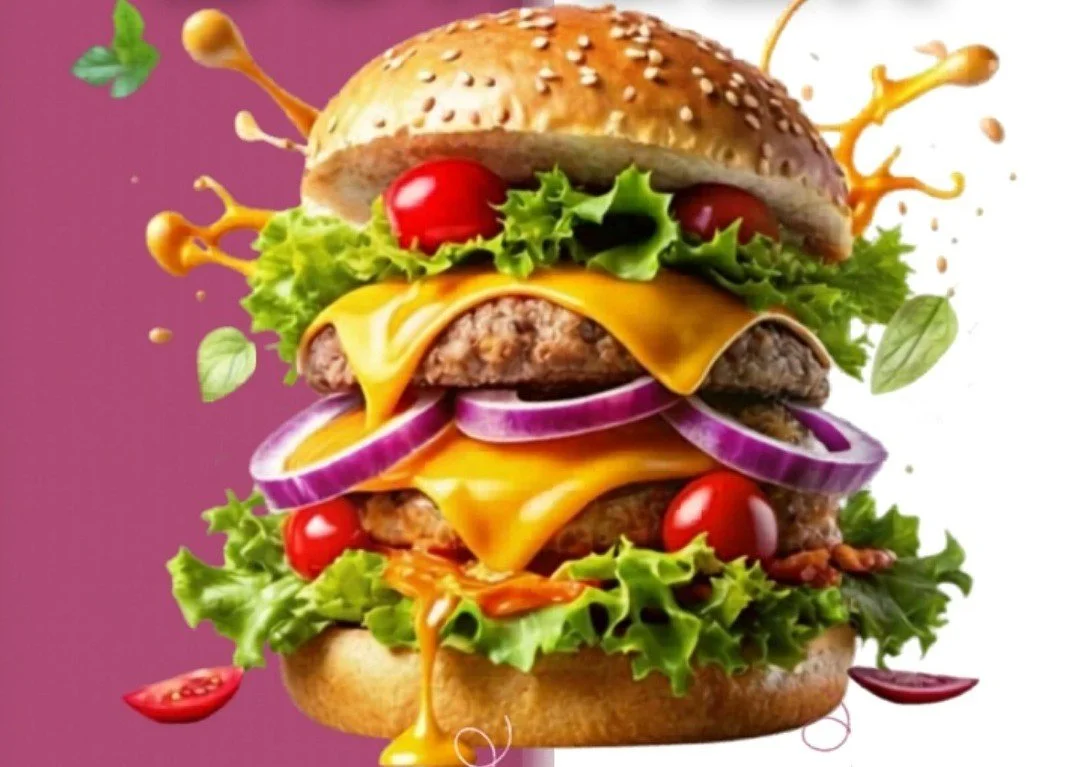 Floating cheeseburger with lettuce, tomato, onion, cheddar cheese, hamburger patties, sesame seed bun, and splashes of mustard and ketchup against a colorful background.