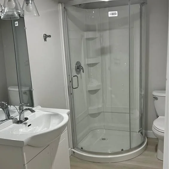 Bathroom with a glass shower enclosure, white sink with a faucet and mirror, and a toilet.