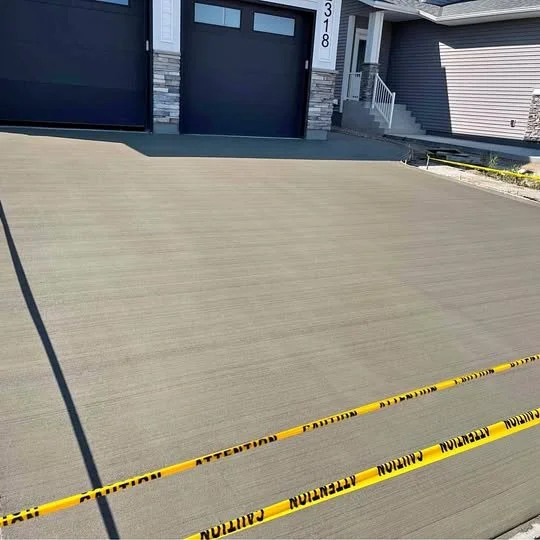 Empty driveway in front of a modern house with two garages, sectioned off with yellow caution tape.