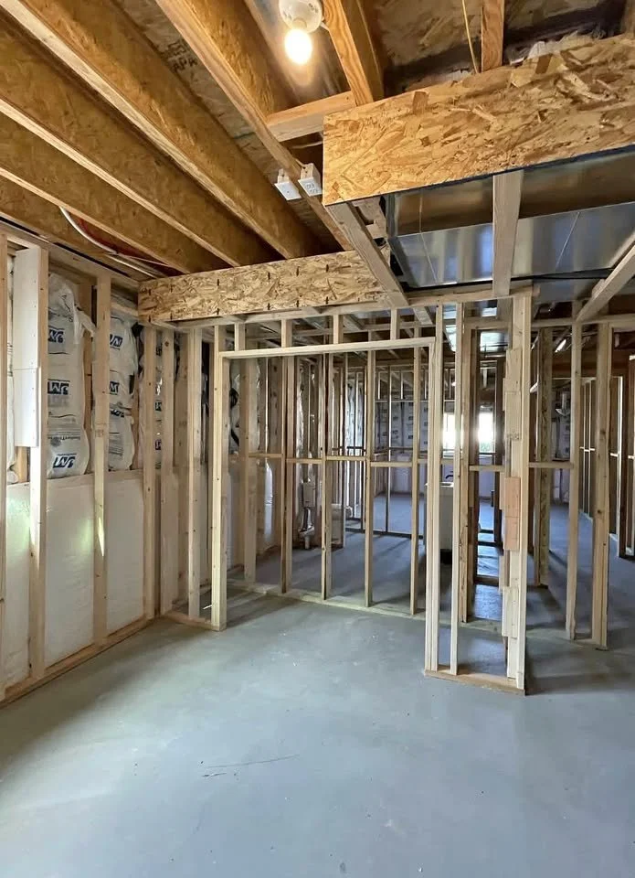 Interior of a house under construction with exposed wooden framing, insulation, and ductwork.