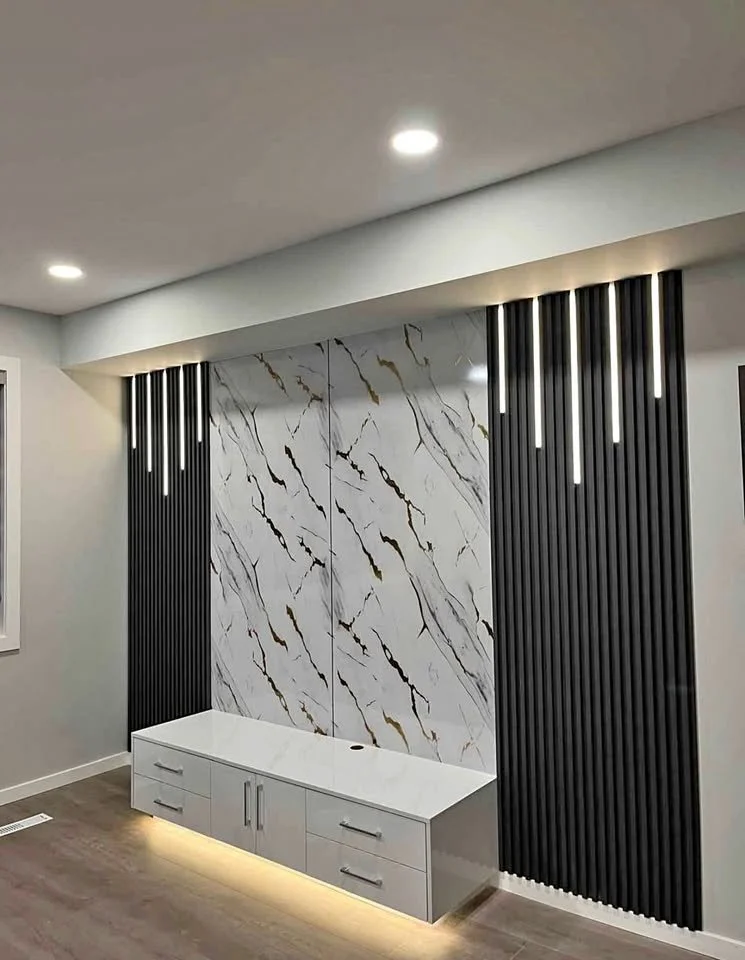 Modern interior wall with marble and black slats, white cabinet with drawers, and LED lighting.