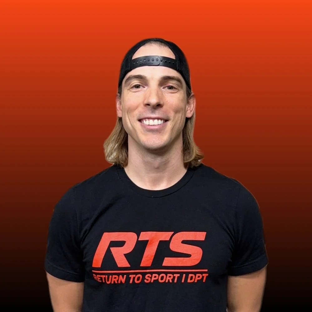 A man with shoulder-length blond hair wearing a black baseball cap backwards and a black T-shirt with red text that reads "RTS Return to Sport I DPT" standing against a gradient orange background.