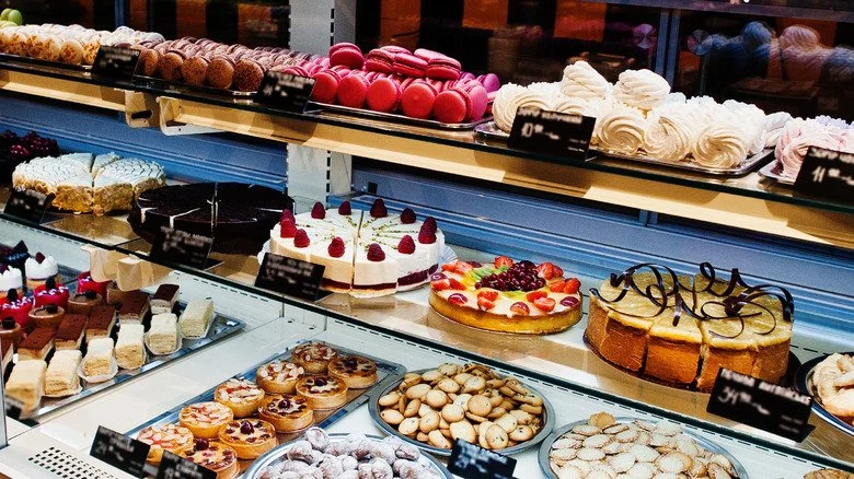 Display case of various desserts including cakes, tarts, macarons, and cookies.