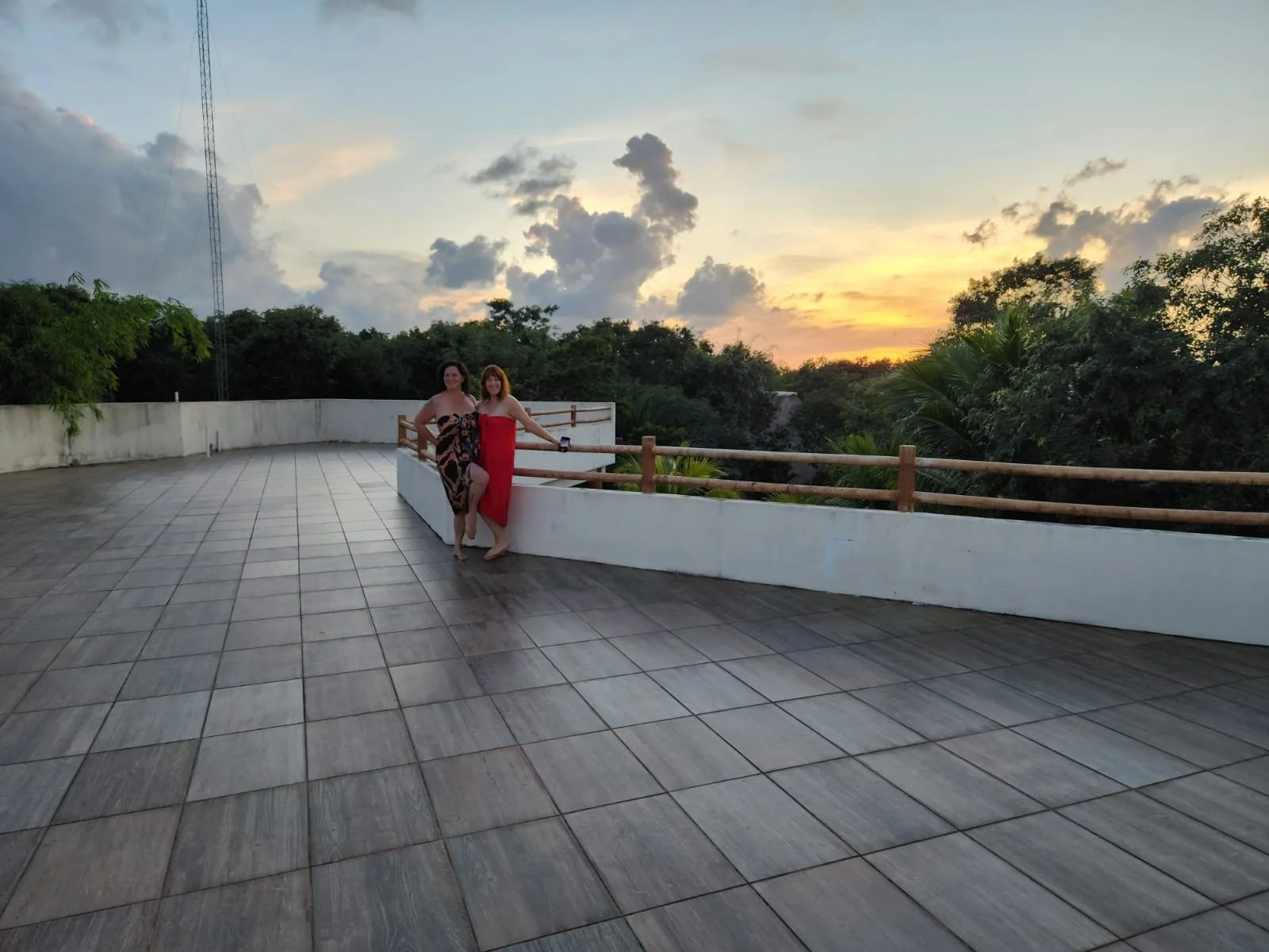 The facilitators of Seducing the Muse, Lara Blackin and Joanna Garner, stand together on a terrace with a sunset sky and trees in the background.