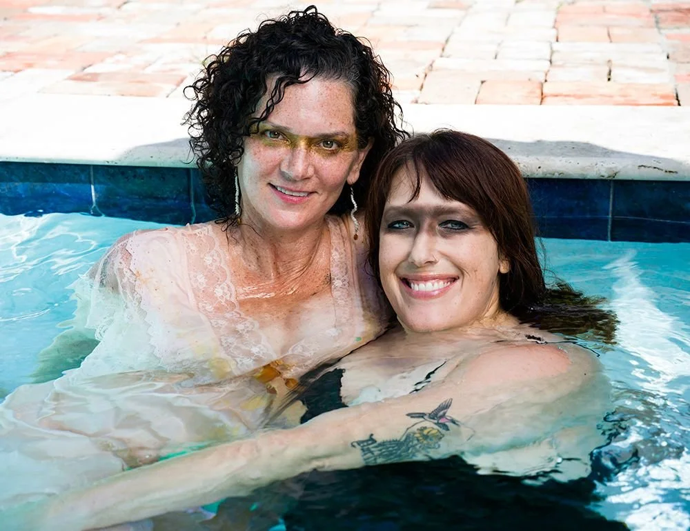 The facilitators of Seducing the Muse, Lara Blackin and Joanna Garner, smiling and relaxing in a swimming pool with bold eye make-up evoking their muses.