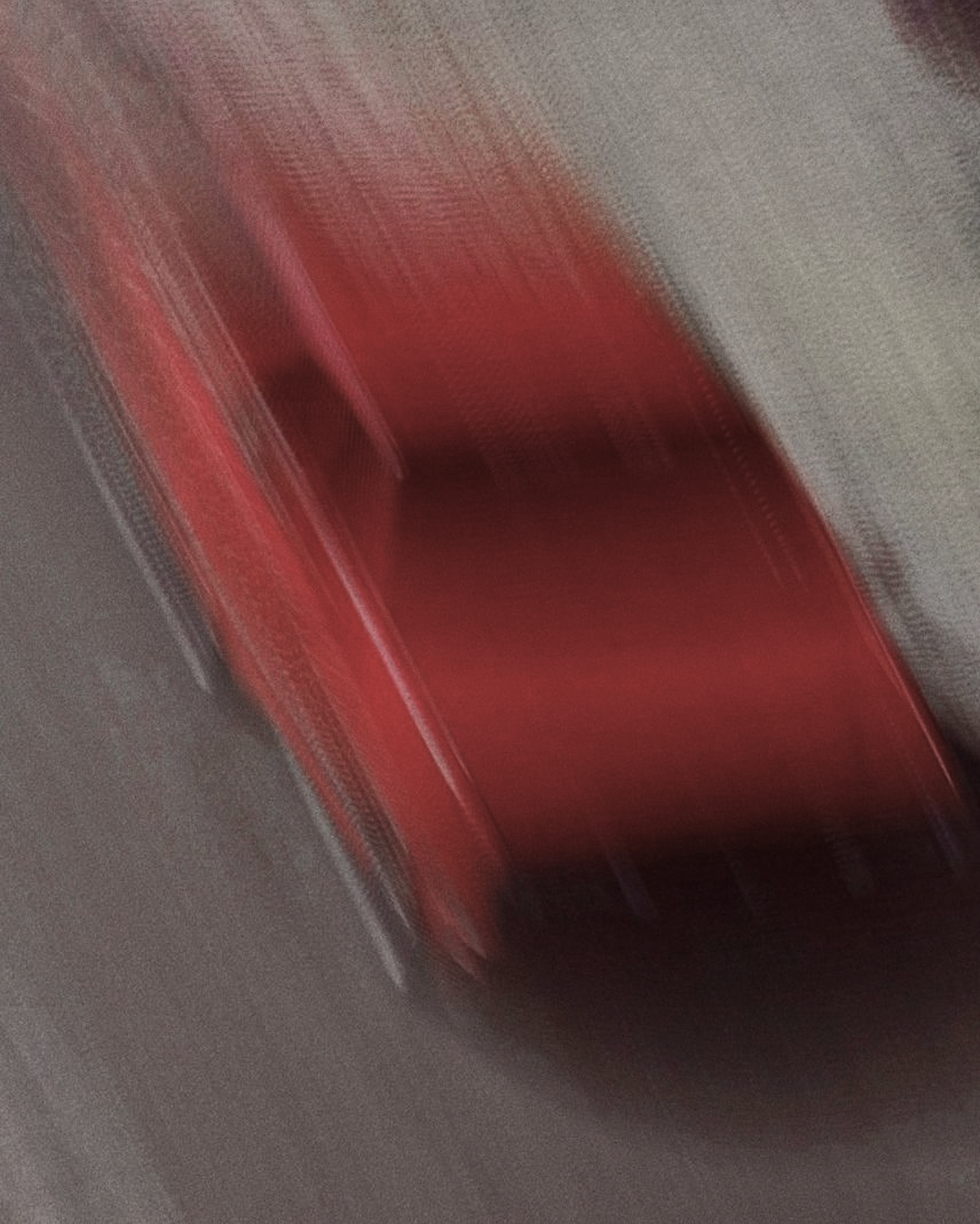 Blurred image with a gray background and streaks of red.