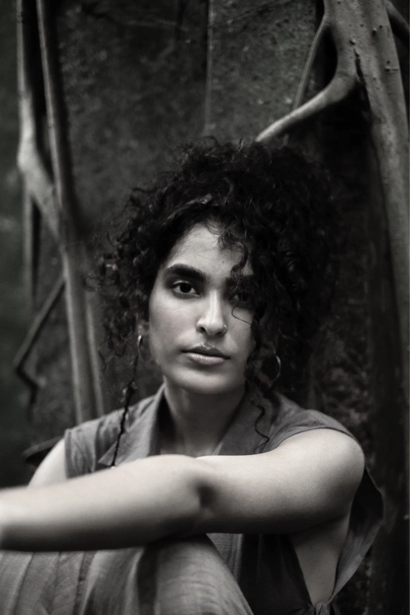 Black and white photo of a woman with curly hair taking a selfie, sitting on the floor with her arm extended.