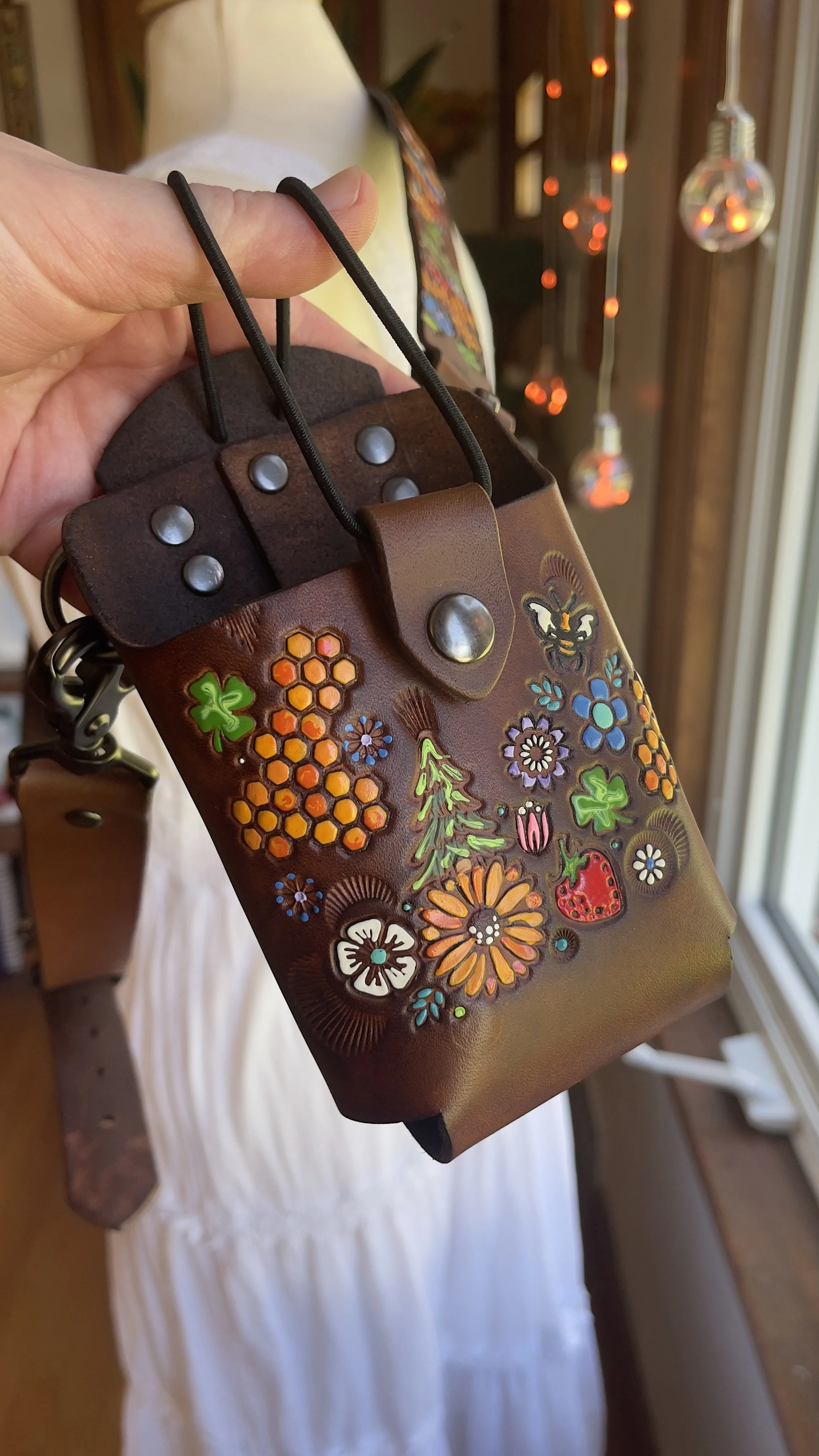 a fire radio holster adorned with stamped flowers, honeycombs, clovers, trees and bees. All designs are handpainted painted in vibrant colors