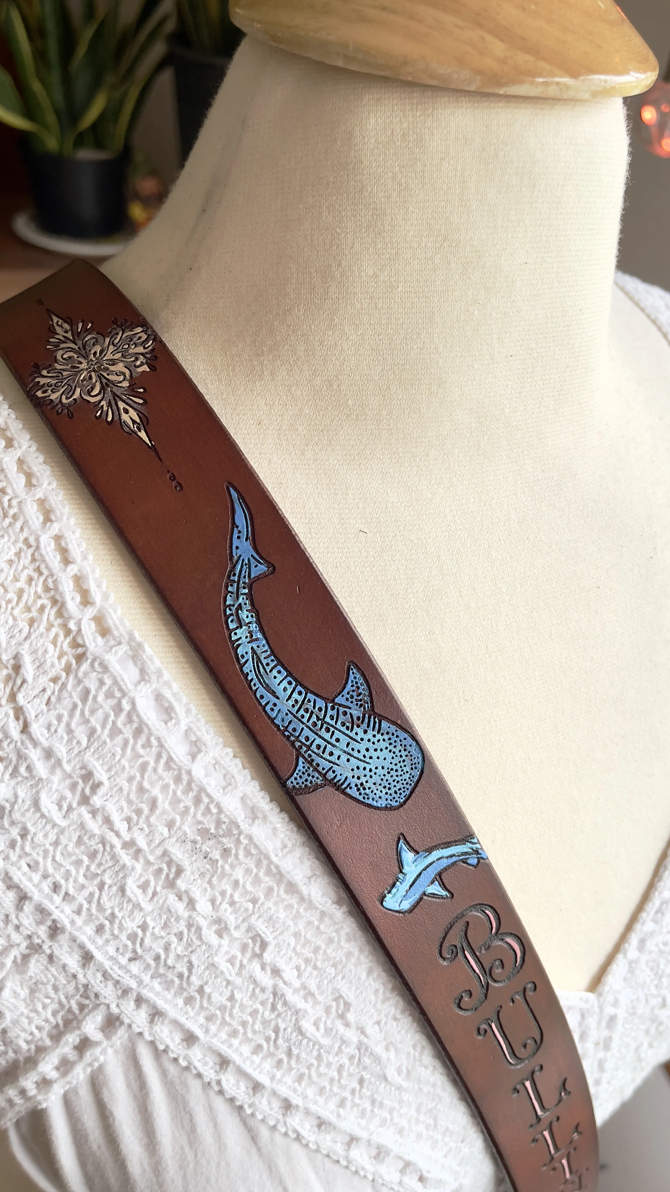 a brown leather fire radio strap with colorful artwork engraved on it. Above the customers name are blue sharks and a decorative design, all handpainted