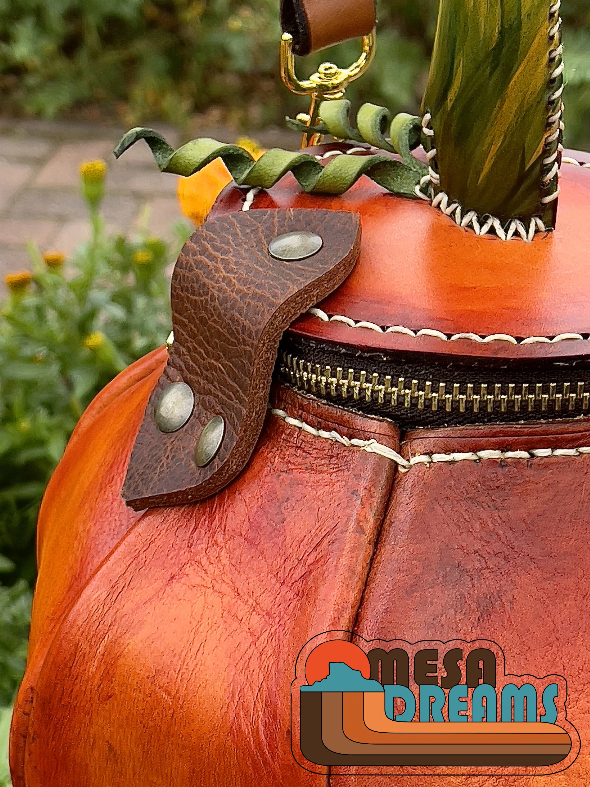 A side view of the Great Pumpkin bag that highlights the brown leather hinge that connects the lid and body of bag. It’s riveted with brass hardware