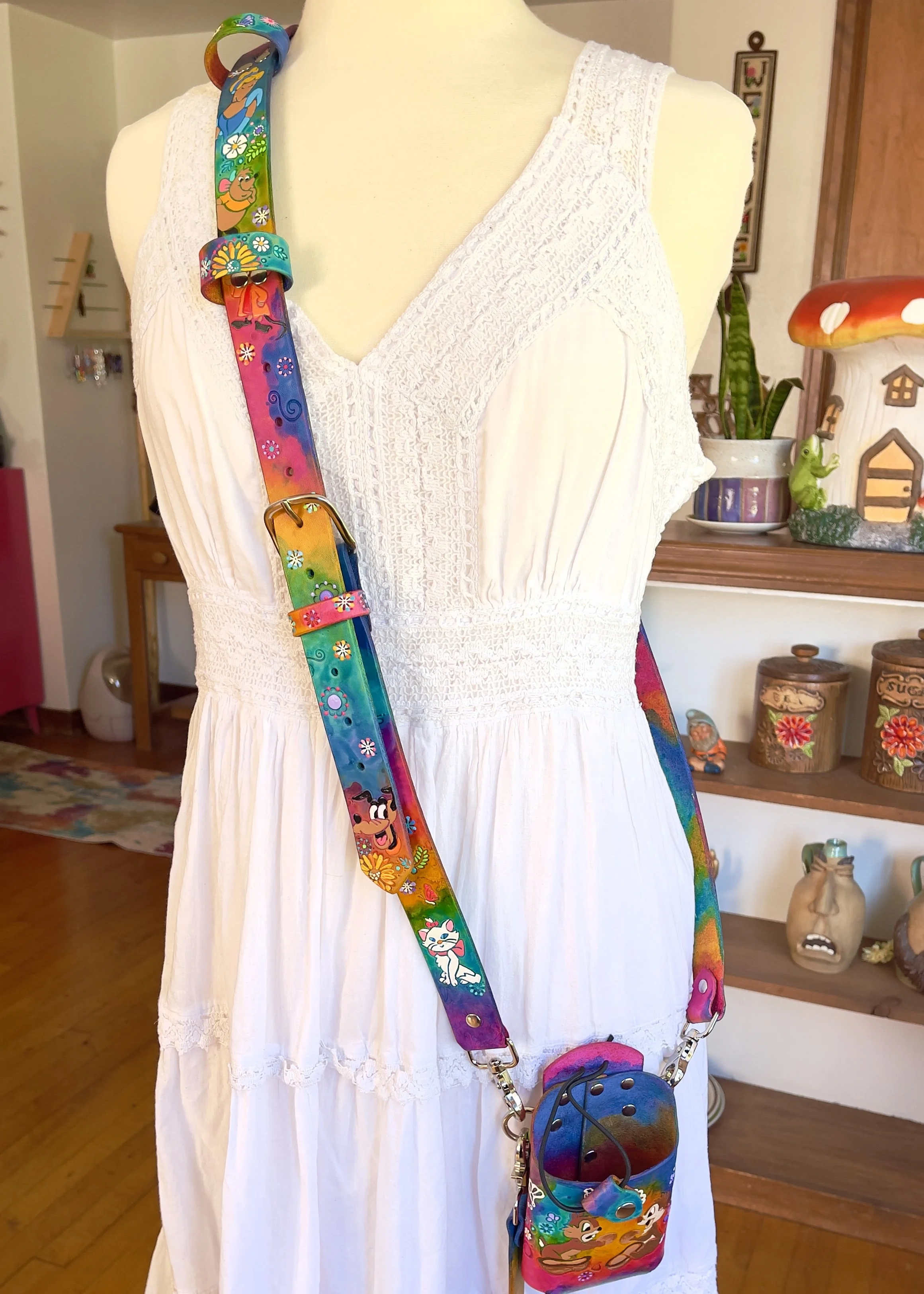 a full view of a fire radio strap and bucket with anti-sway strap. They are stained in an array of bright colors and have fun cartoon characters engraved on the leather.